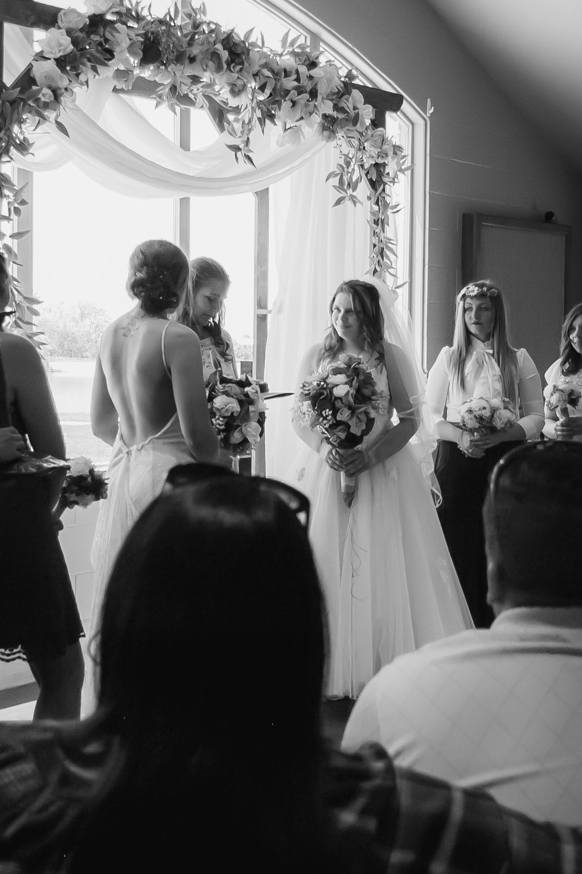 A black and white photo of a wedding ceremony with guests watching in an elegant indoor venue.