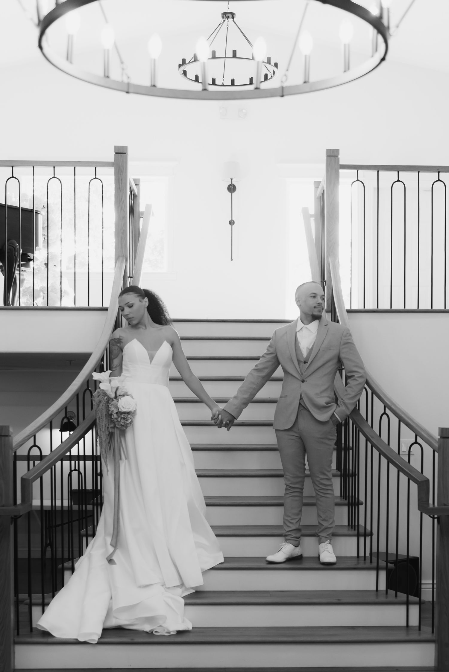 A wedding dress and formal attire displayed on grand white stairs with black railings.