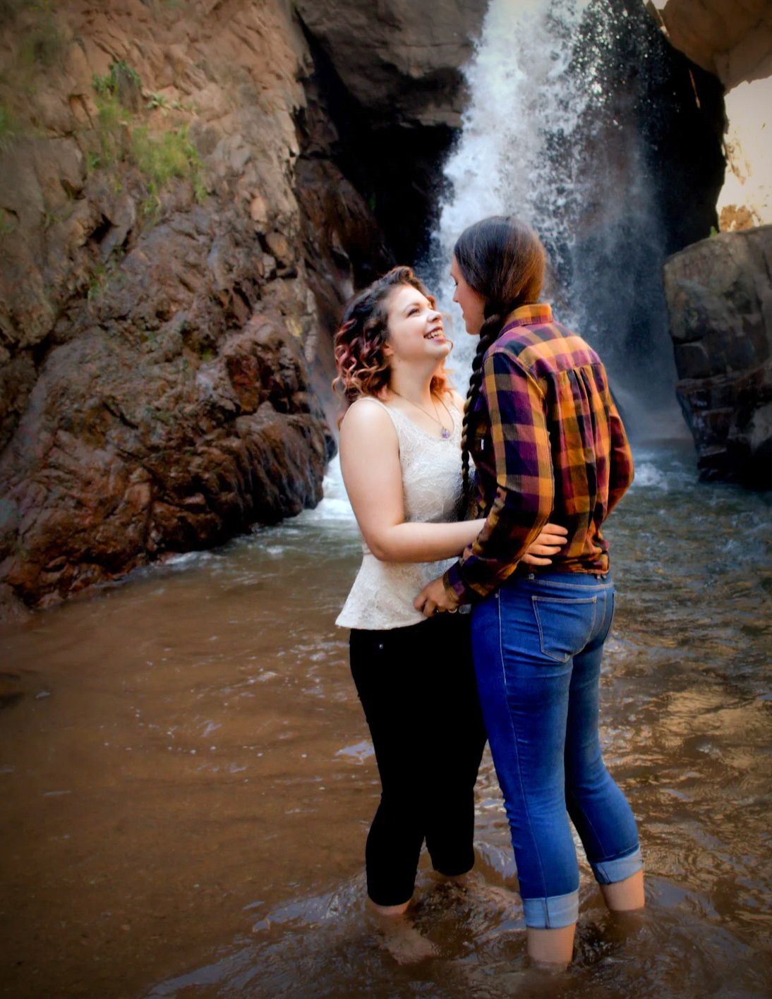 A couple shares intimate moments near a scenic waterfall.