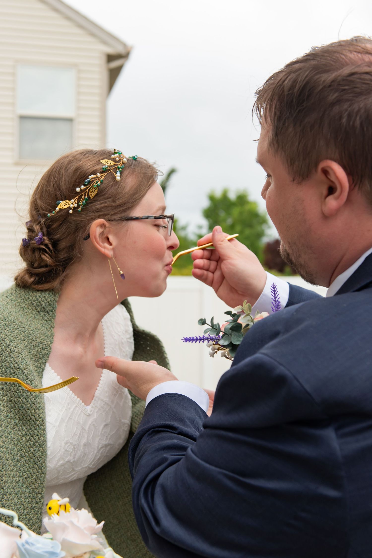 Close up of couple feeding each other cake at an outdoor wedding.