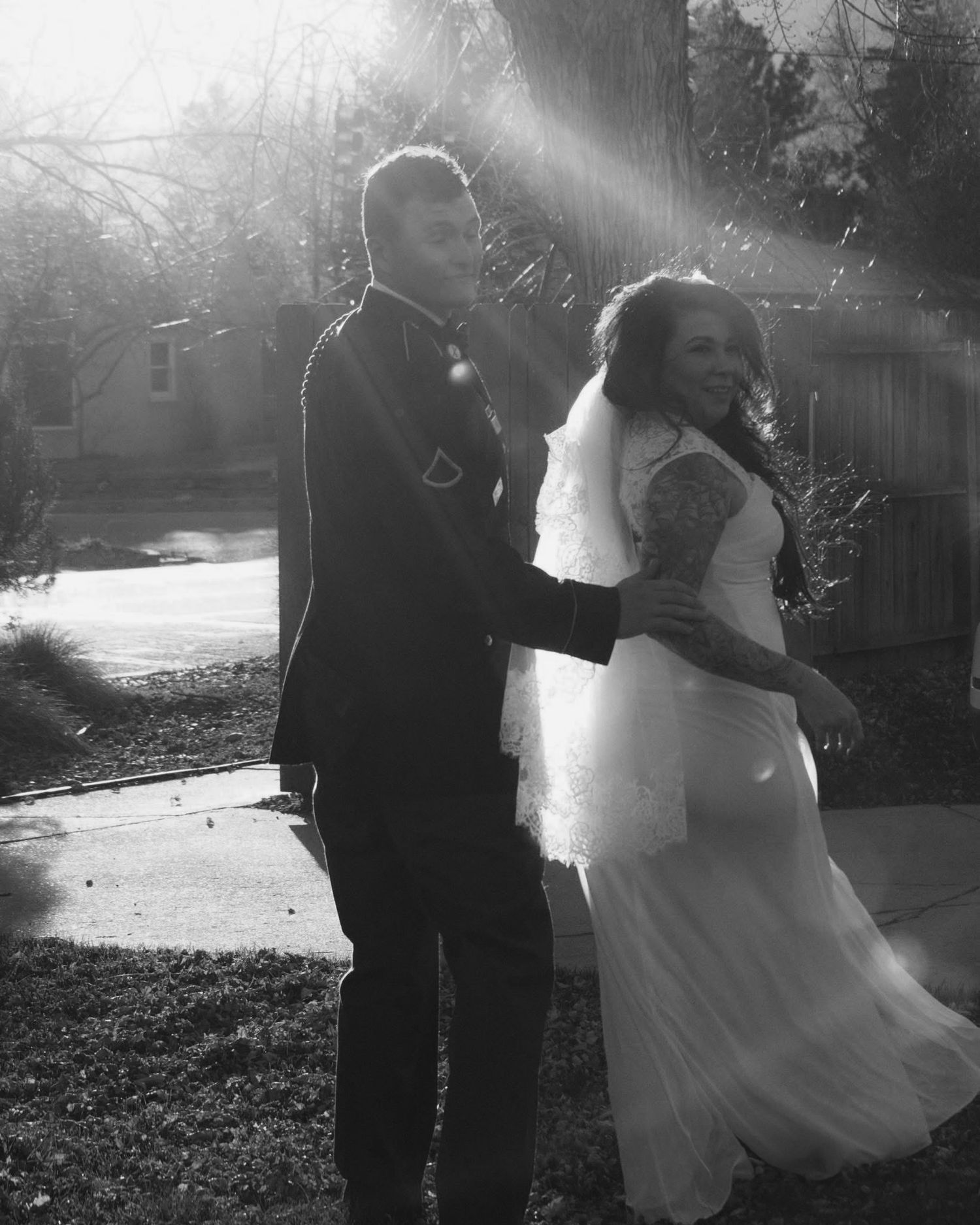 A silhouetted couple embraces in dreamy black and white photography outdoors.