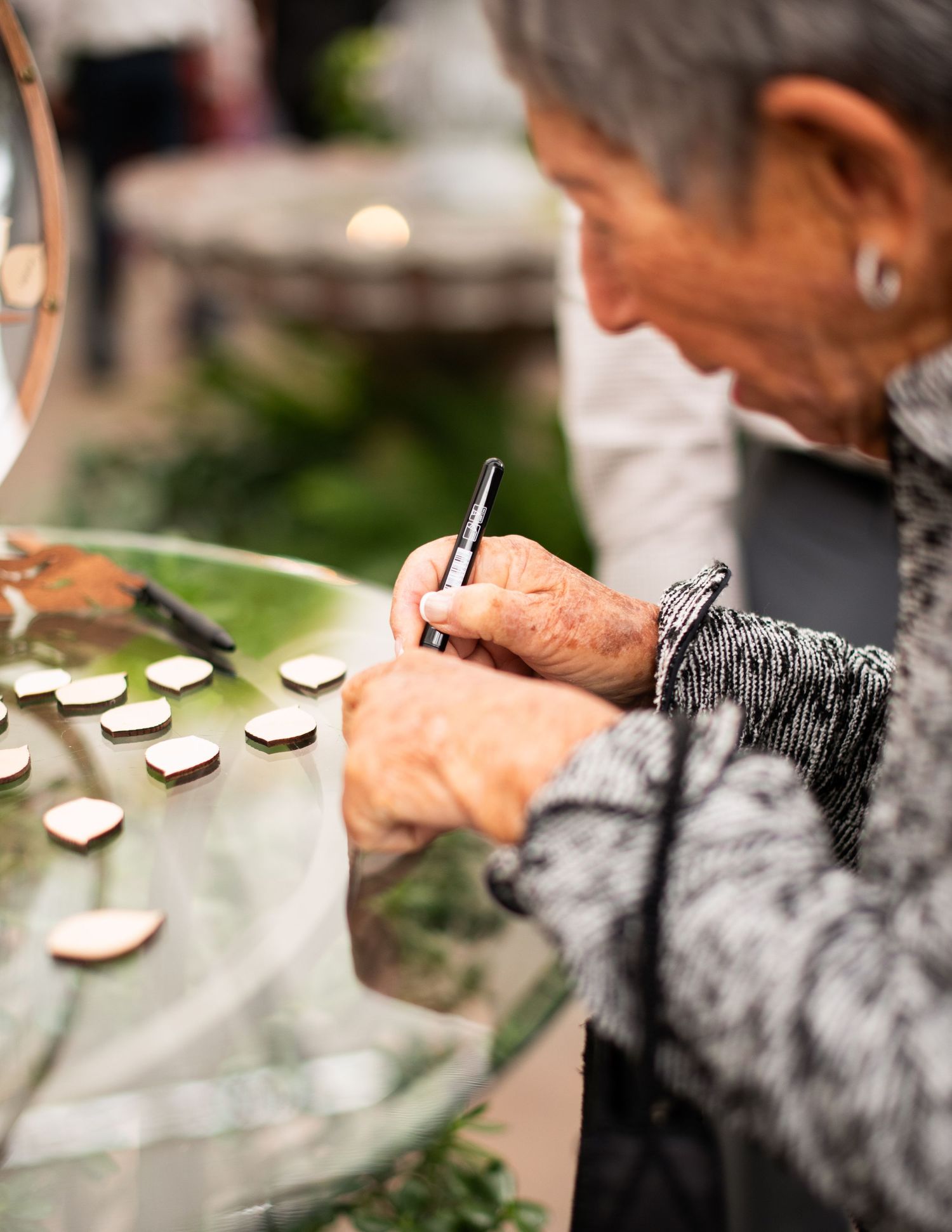 Close up of hands signing a wedding document with wooden hearts scattered nearby.