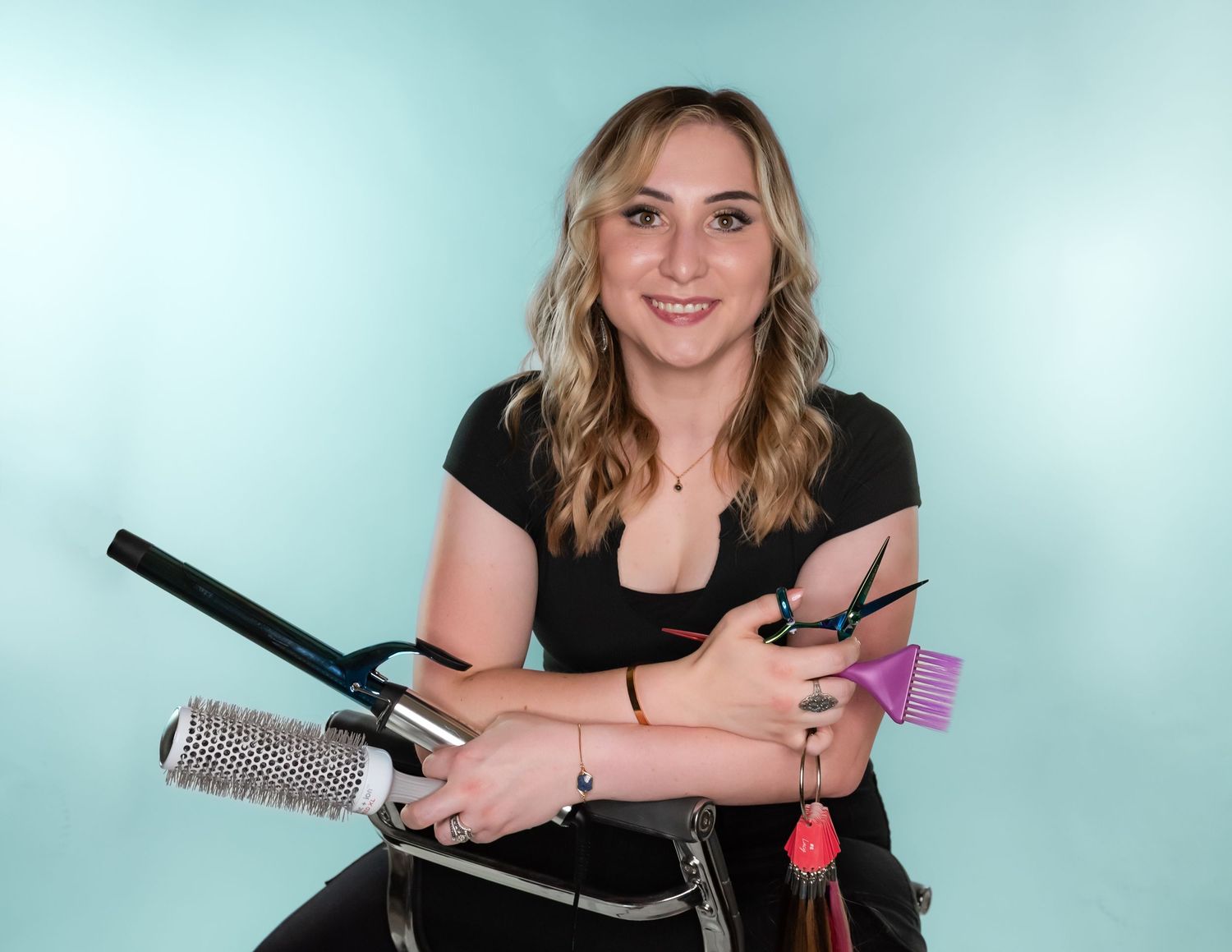 Professional photographer posing with camera equipment against light blue backdrop.