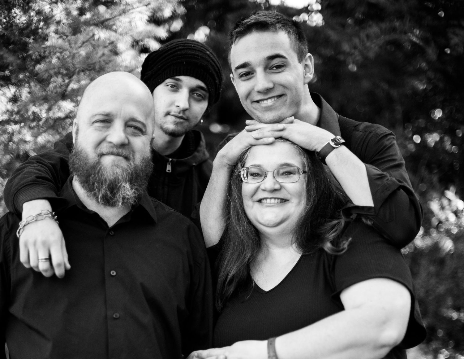 Candid family portrait series outdoors with natural expressions and black attire.