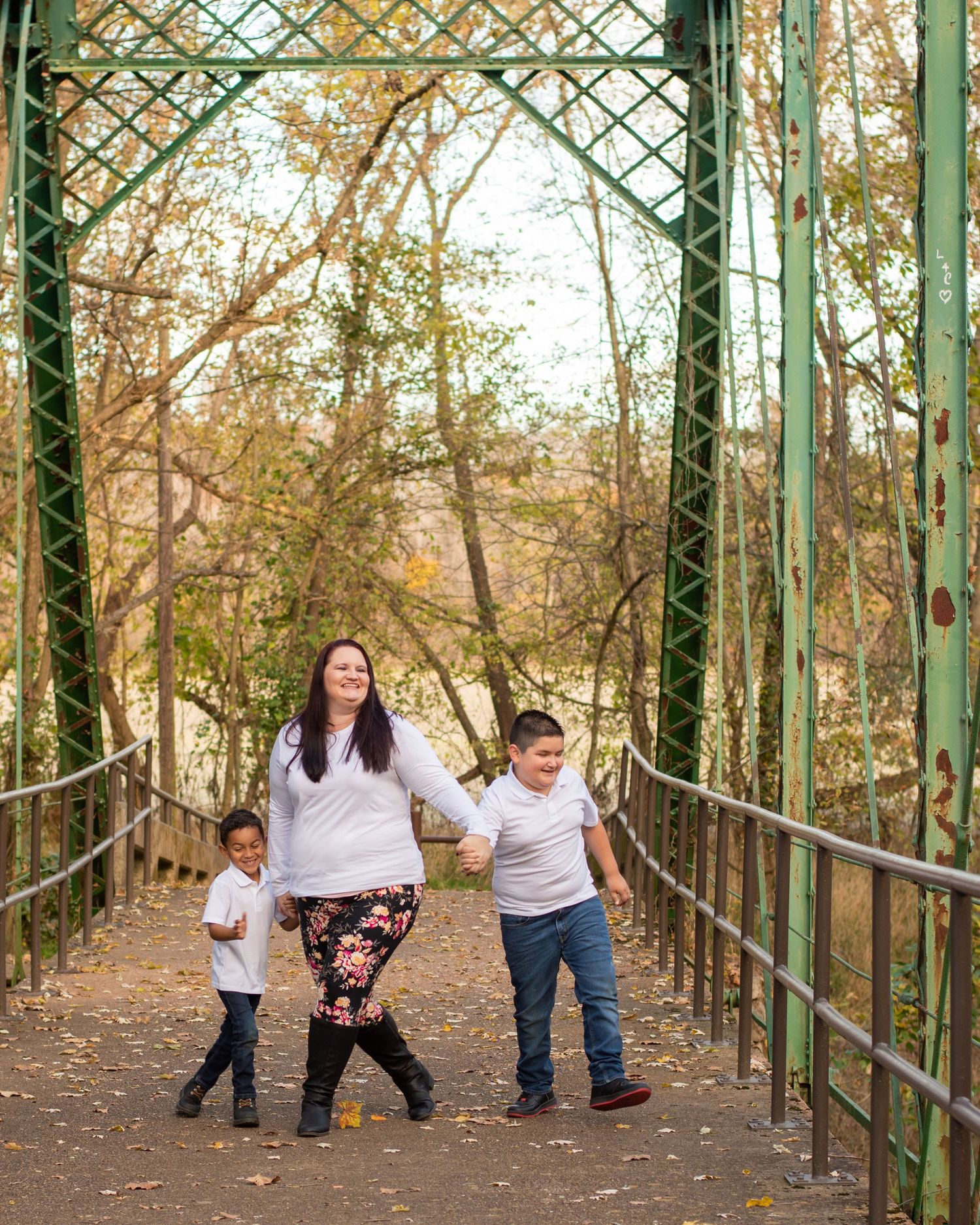 Family walking through green metal archway tunnel surrounded by autumn foliage.