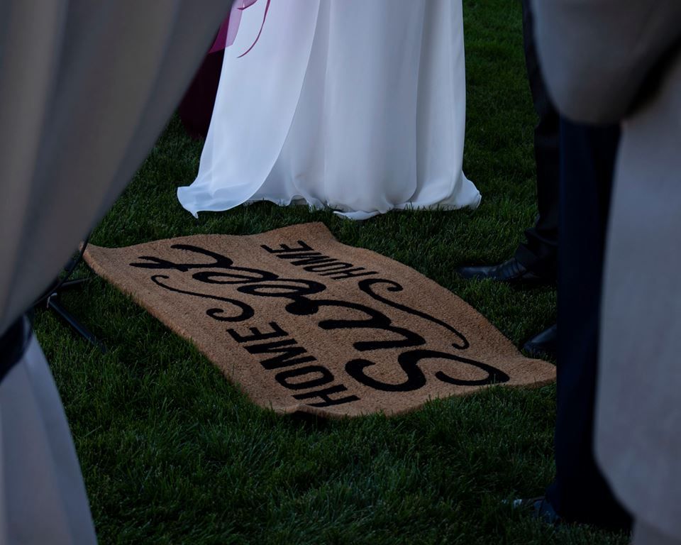 Wedding dress hem flowing over rustic wooden signs on grass.