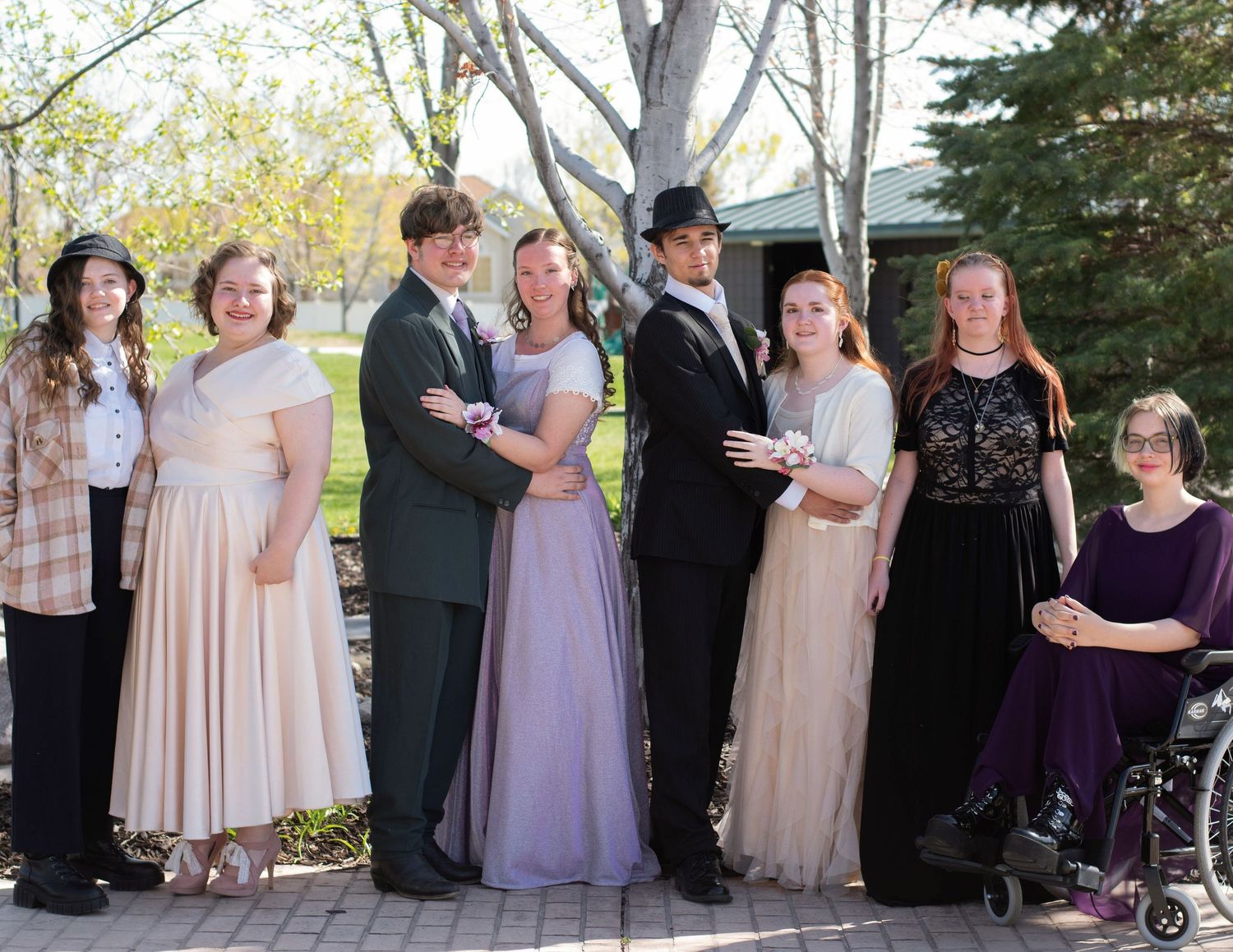 Wedding party group photo with pastel dresses outdoors in spring setting.