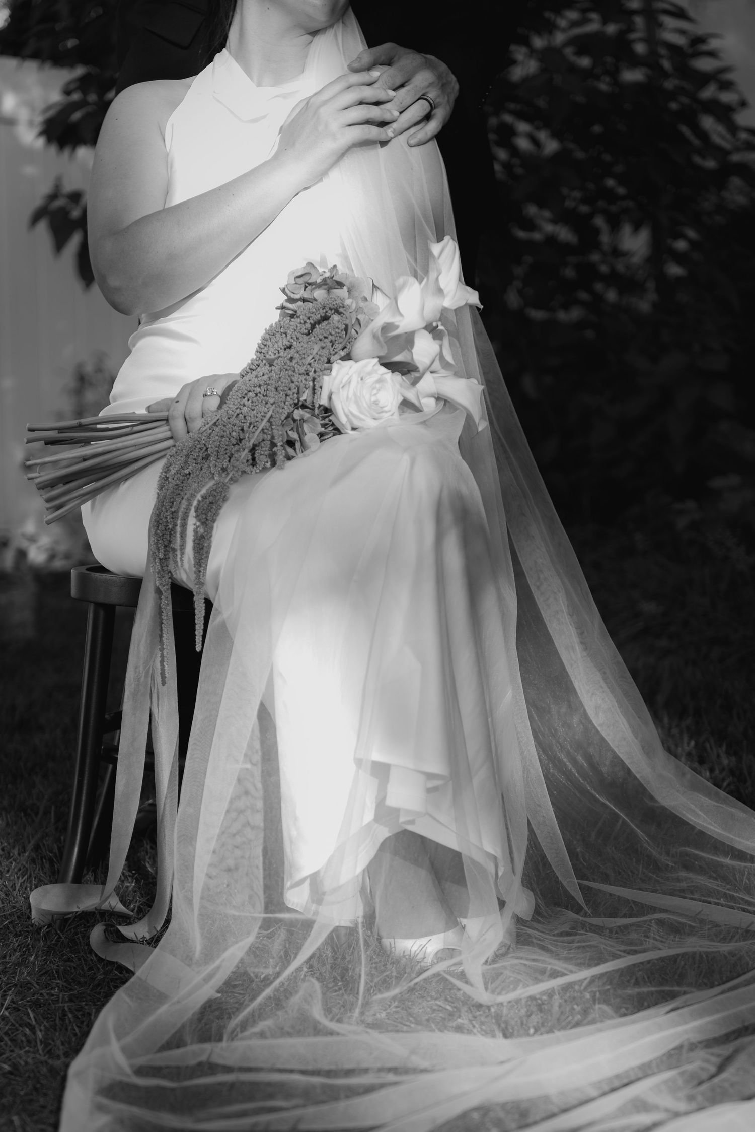 Close-up details of a flowing white wedding dress with delicate lace and tulle fabric in black and white.