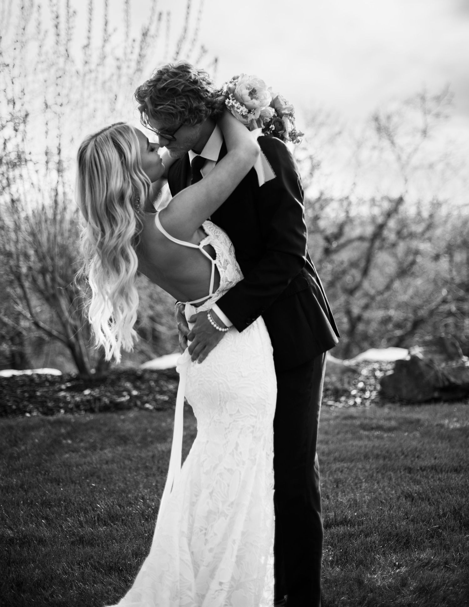 Black and white portrait of a couple in wedding attire embracing outdoors.