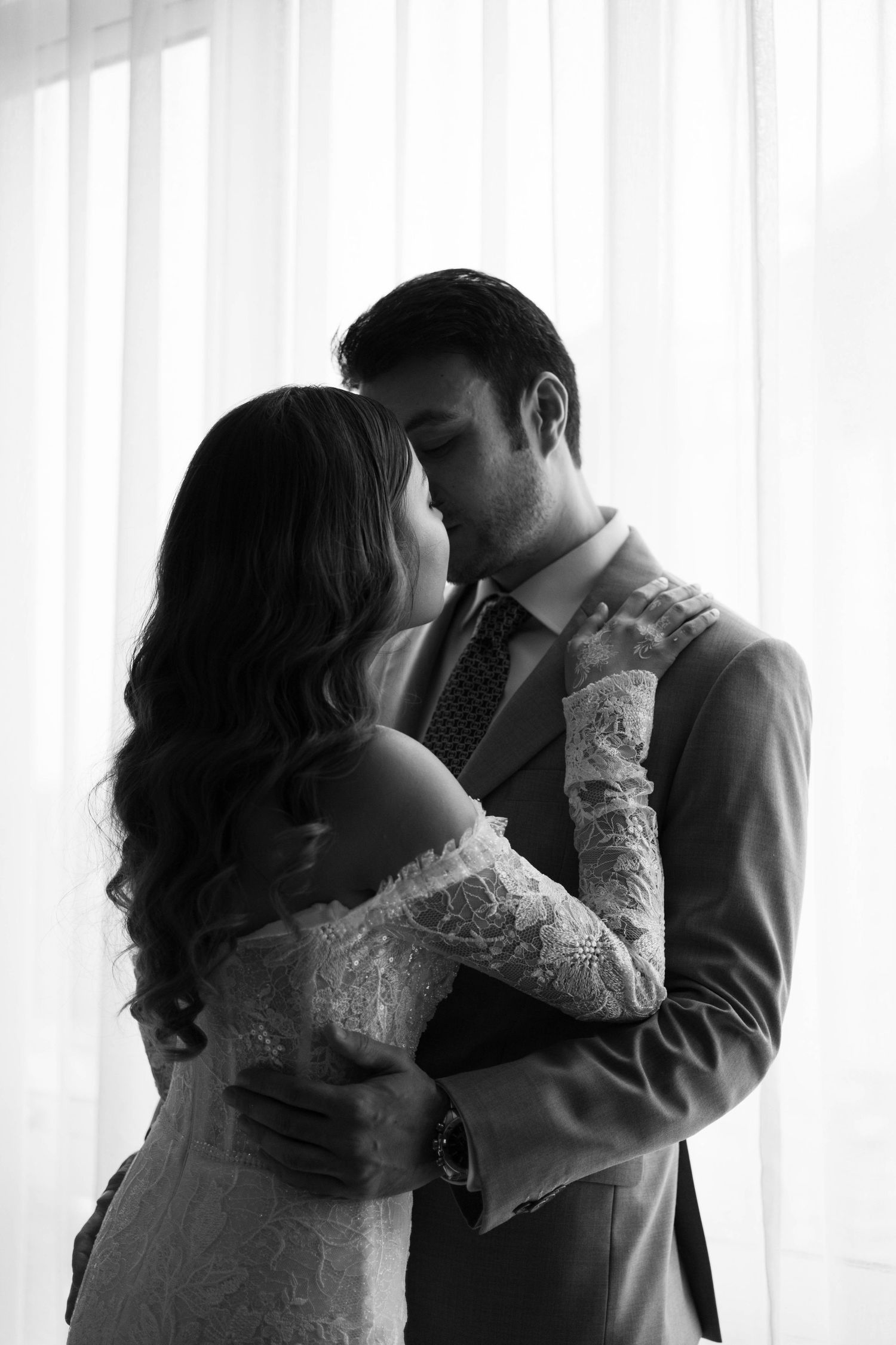 Silhouetted wedding couple sharing tender moments against white curtained windows in Kuala Lumpur by Crossfadefilm