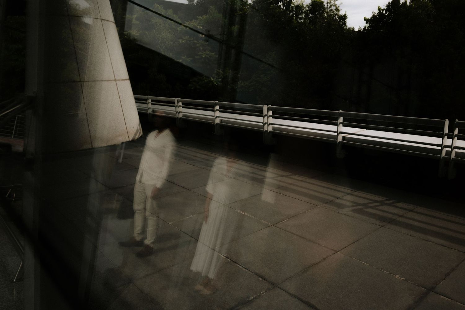 A person stands alone on an empty subway platform with bright overhead lighting creating dramatic shadows.