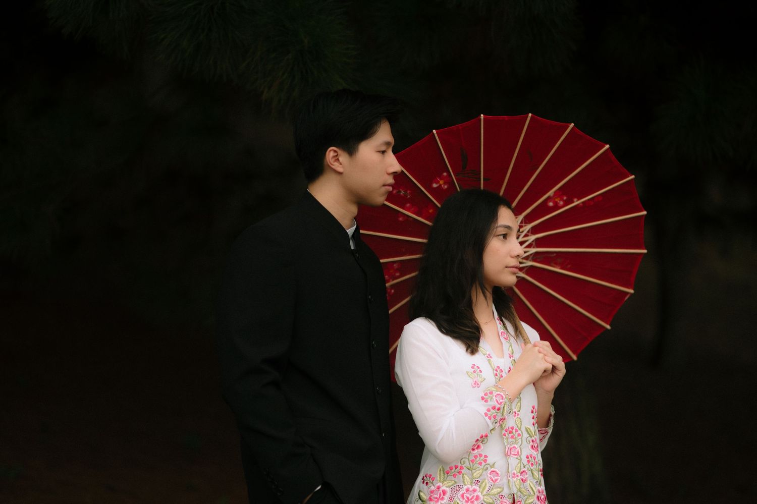 A sequence of romantic dance poses with traditional red parasols against a dark background.