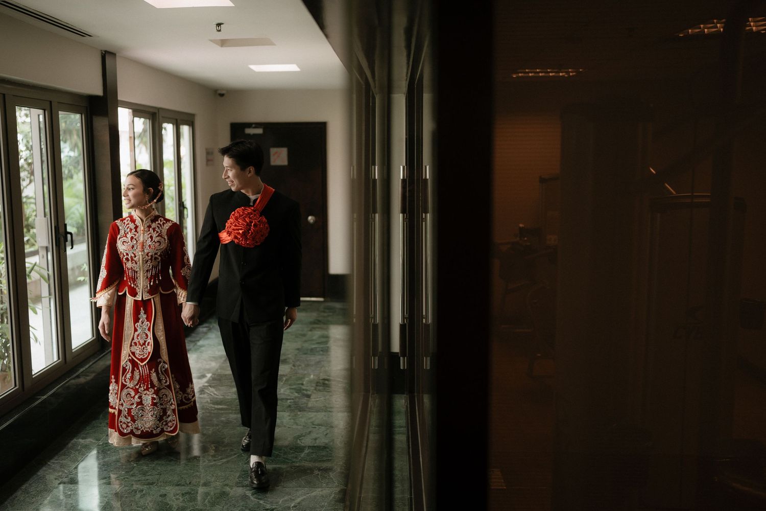 A hallway view showing multiple people walking through a building corridor with windows and natural lighting.