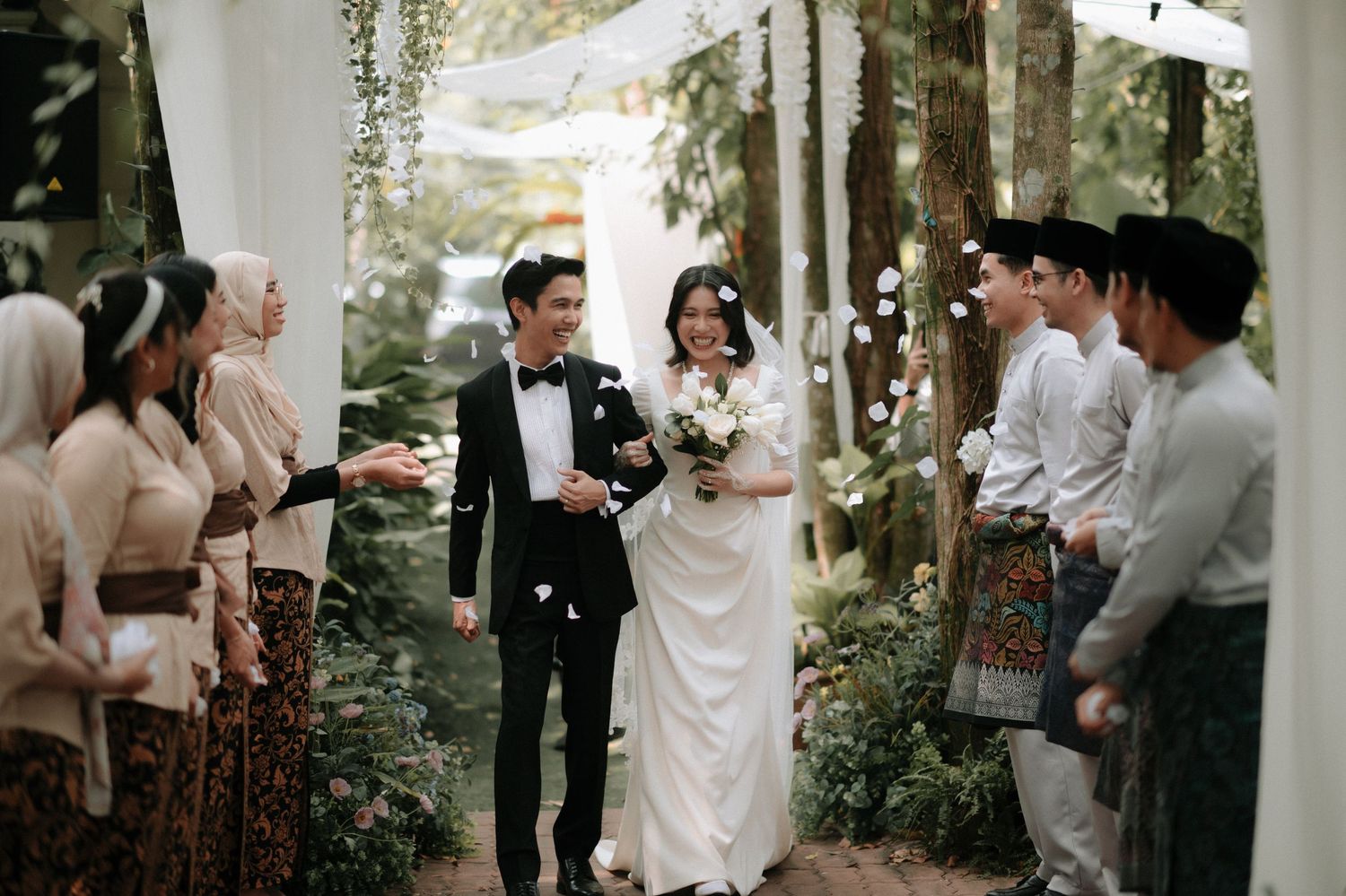 Wedding guests dance and celebrate together in an outdoor garden reception setting.