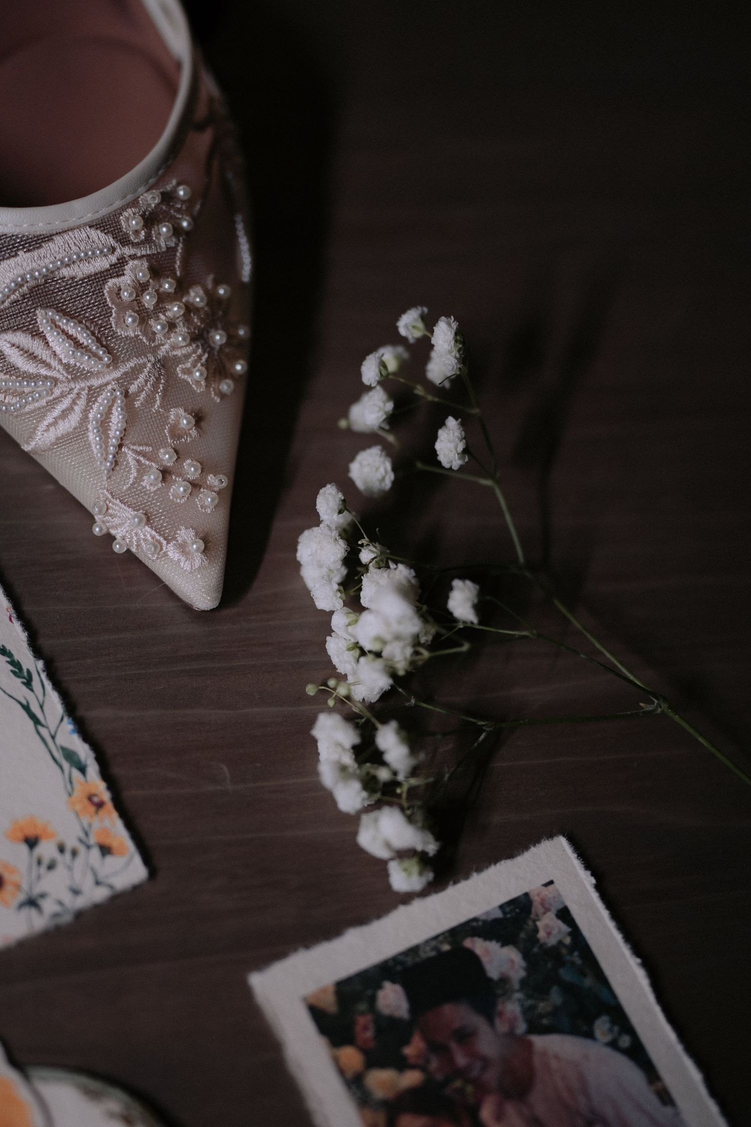 Wedding details with white flowers and lace decorations arranged on dark wooden surface captured by Crossfadefilm