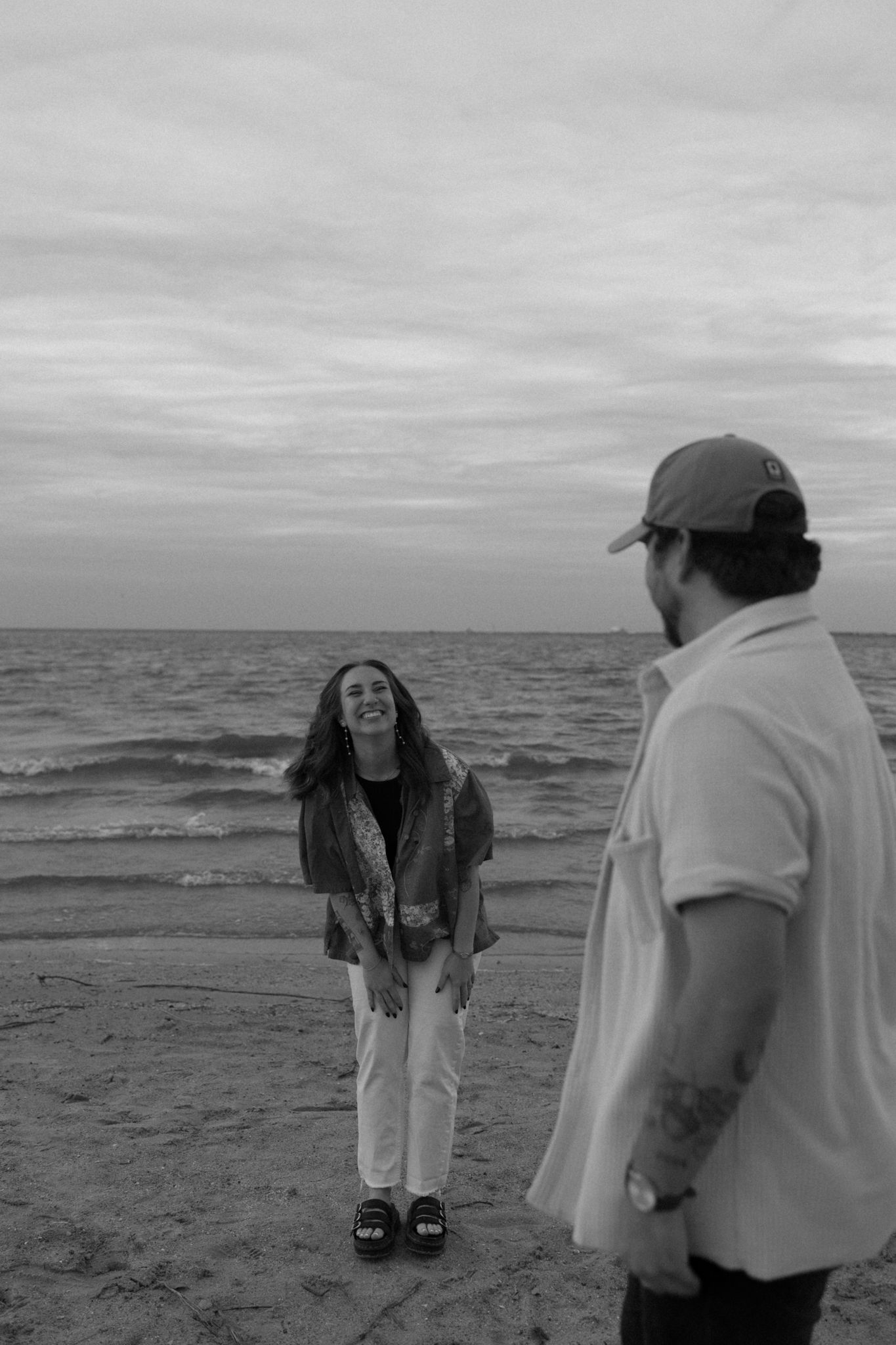 A couple enjoying a lighthearted moment together on a beach with waves in the background.