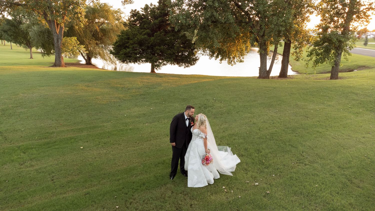 Romantic wedding couple portraits at sunset in a lush green outdoor setting.
