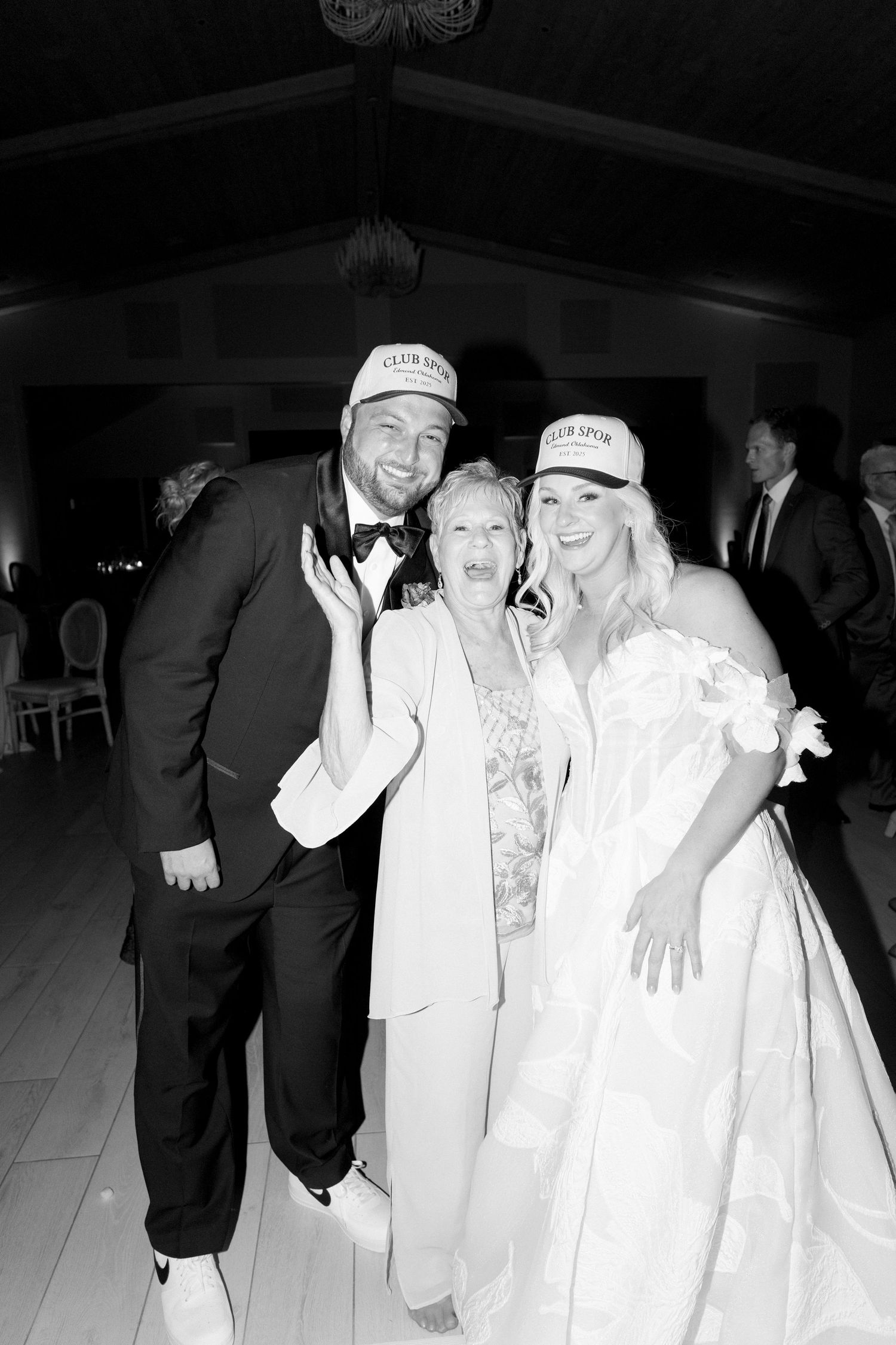 Wedding party celebrating and laughing together in formal attire at an indoor reception venue.