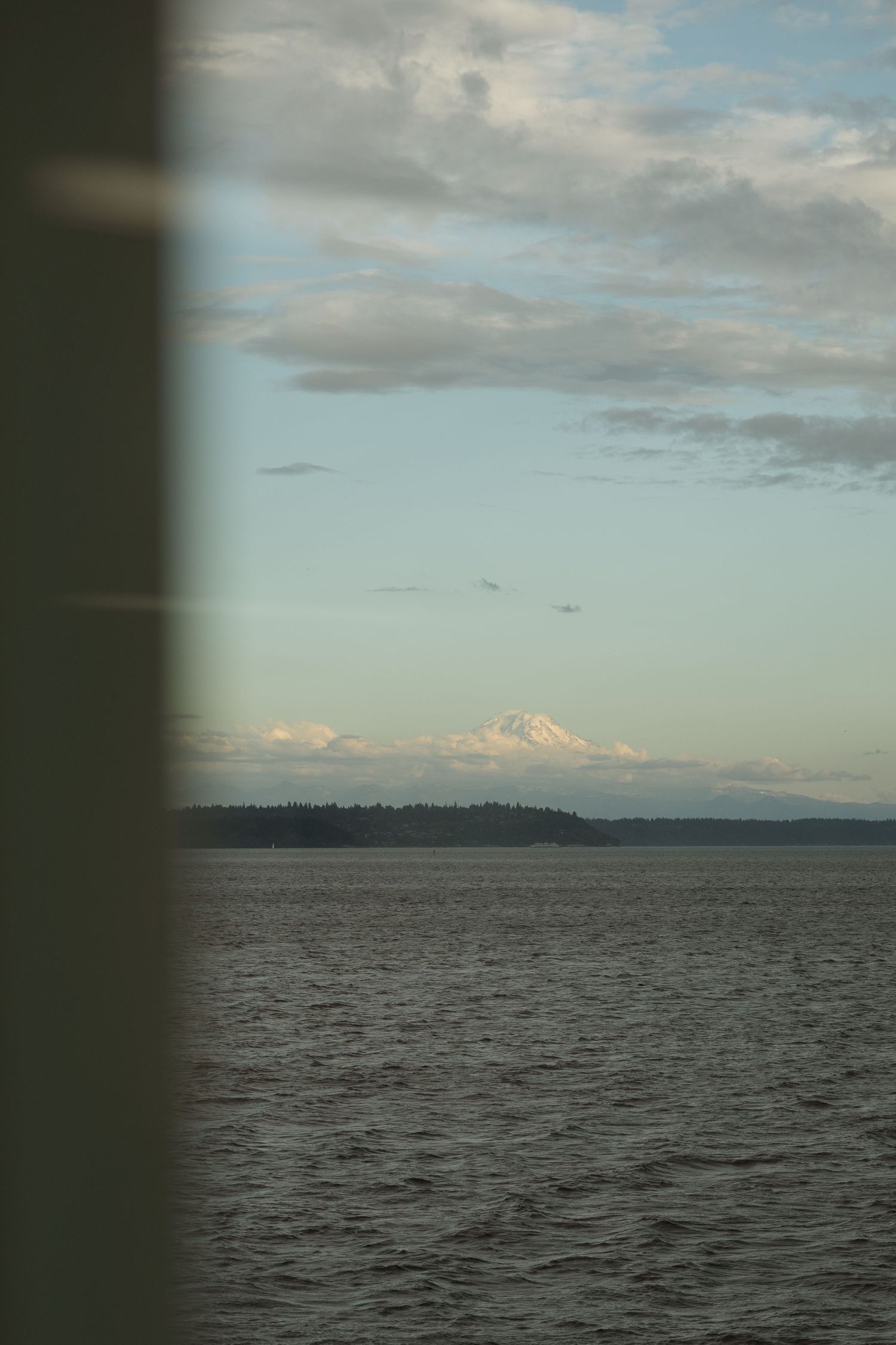 Scenic view of Mount Rainier and Puget Sound through ferry window at sunset.