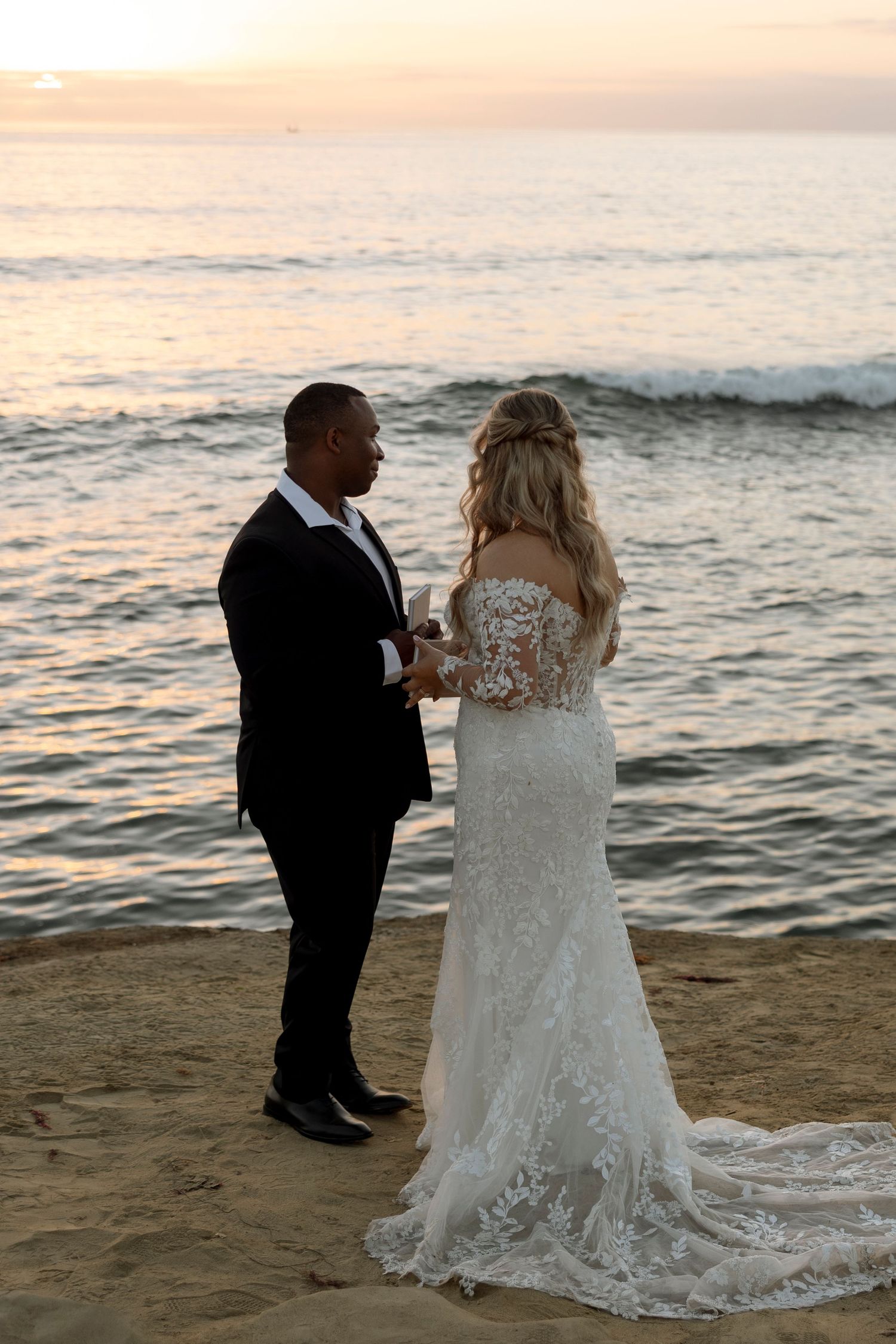 A sunset beach wedding ceremony with waves and golden light in the background.