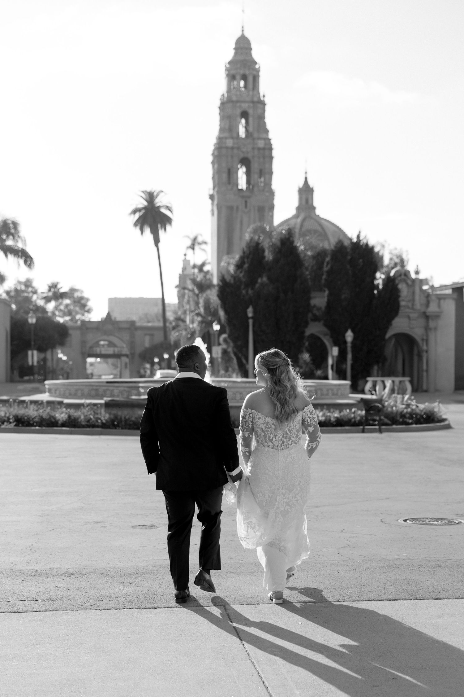 Silhouetted couple walking together near a Spanish colonial style building with bell towers.