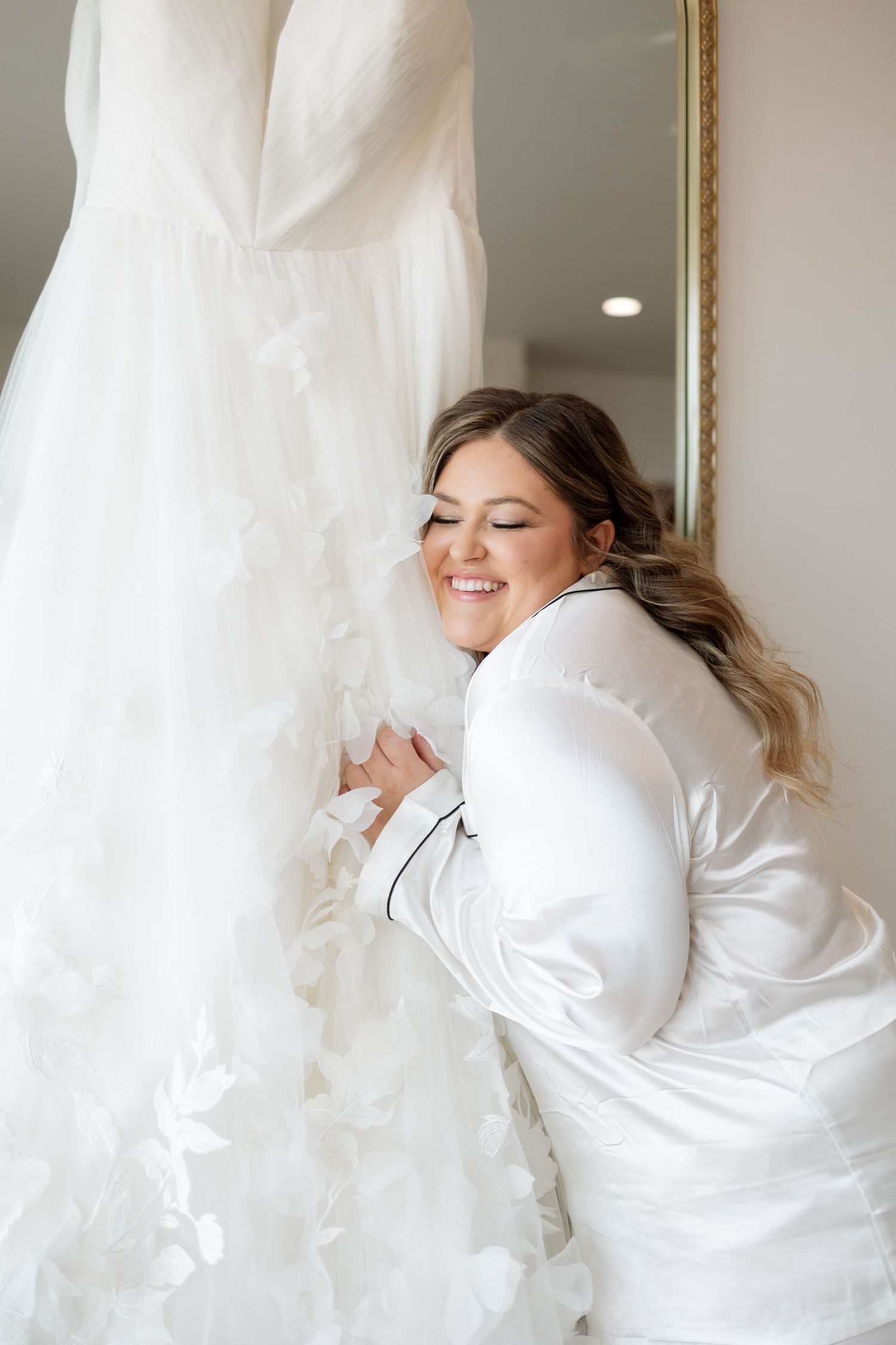 Joyful moment with bridal gown hanging in background.