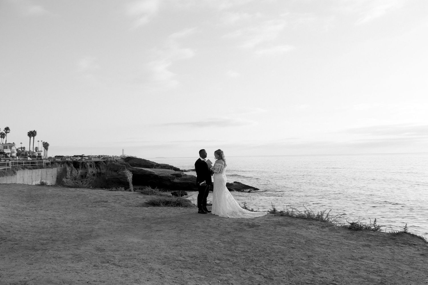 A scenic coastal view with waves crashing against rocky cliffs under a cloudy sky at sunset.