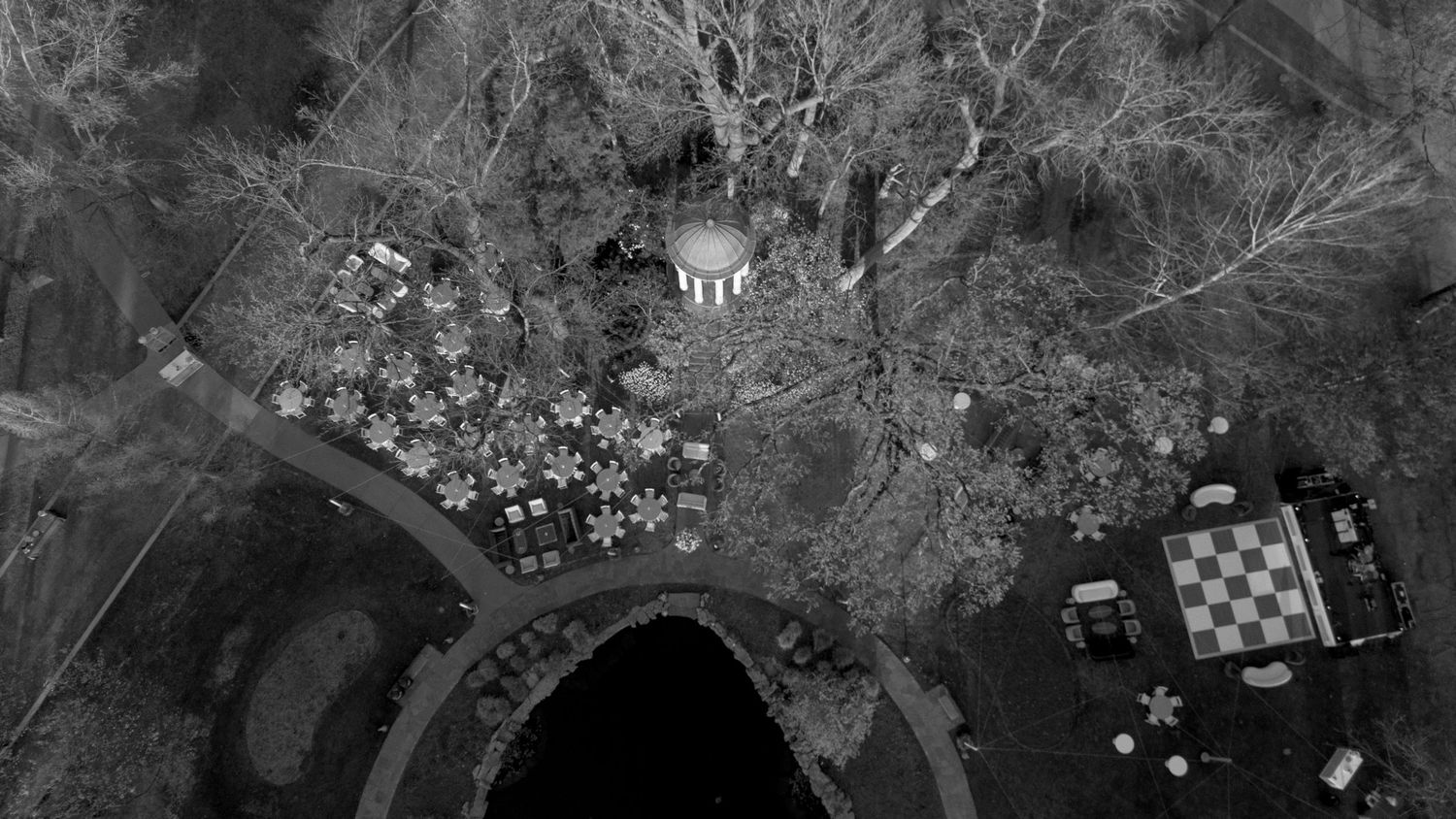 Aerial black and white view of outdoor wedding reception with rotunda and round tables.