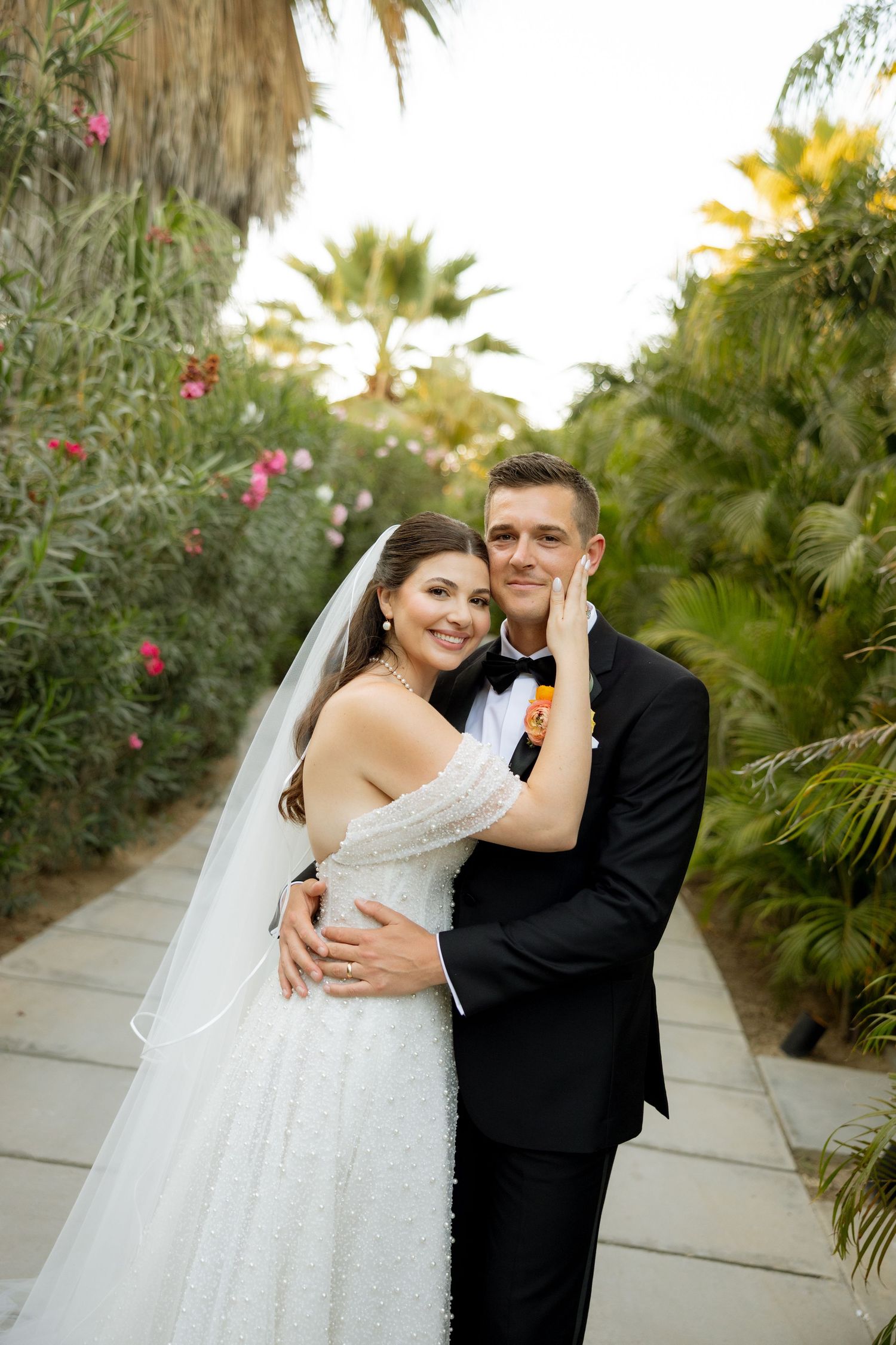 Happy bride and groom embracing on a lush tropical garden pathway on their wedding day.