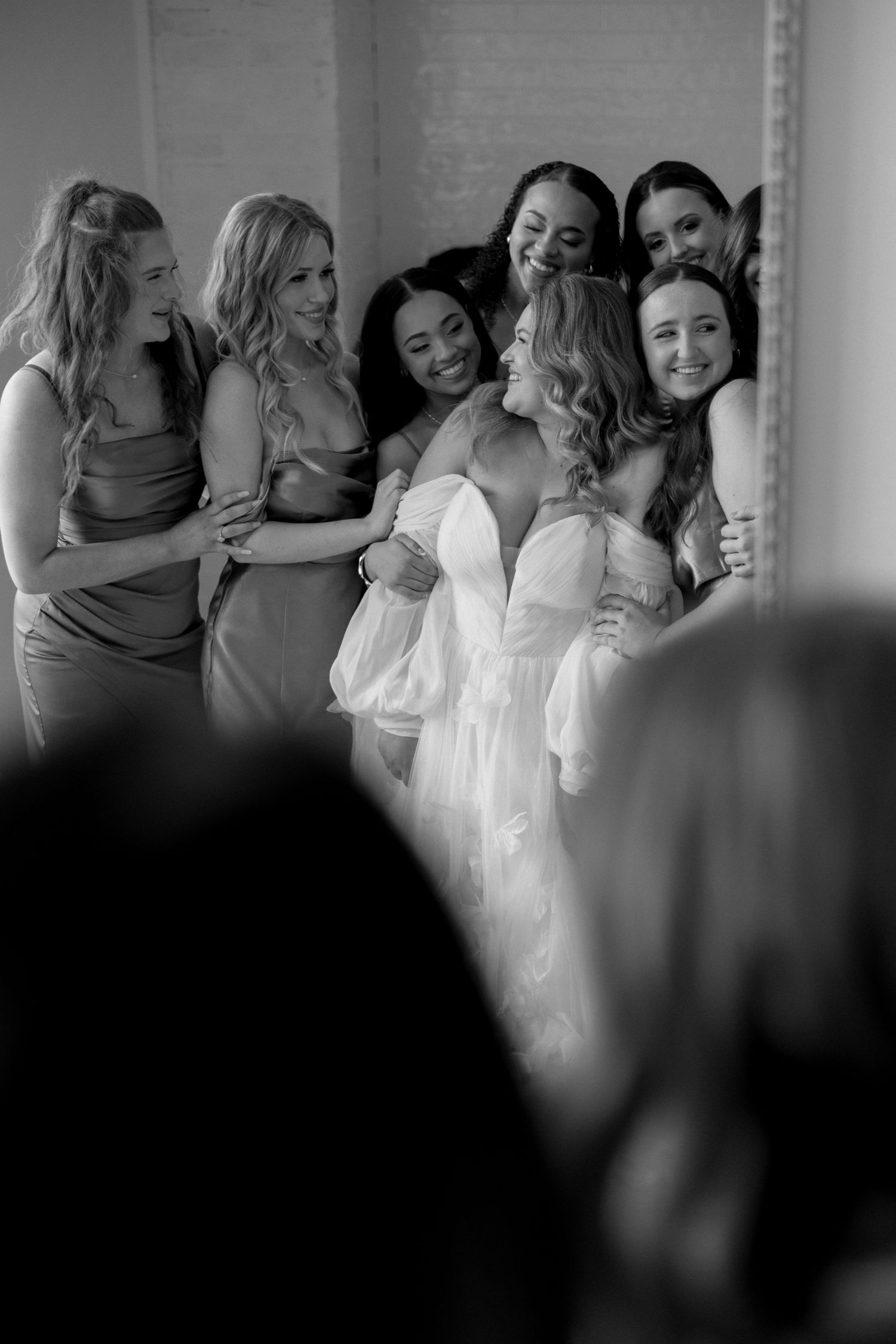An intimate black and white photo of bridesmaids sharing a special moment.