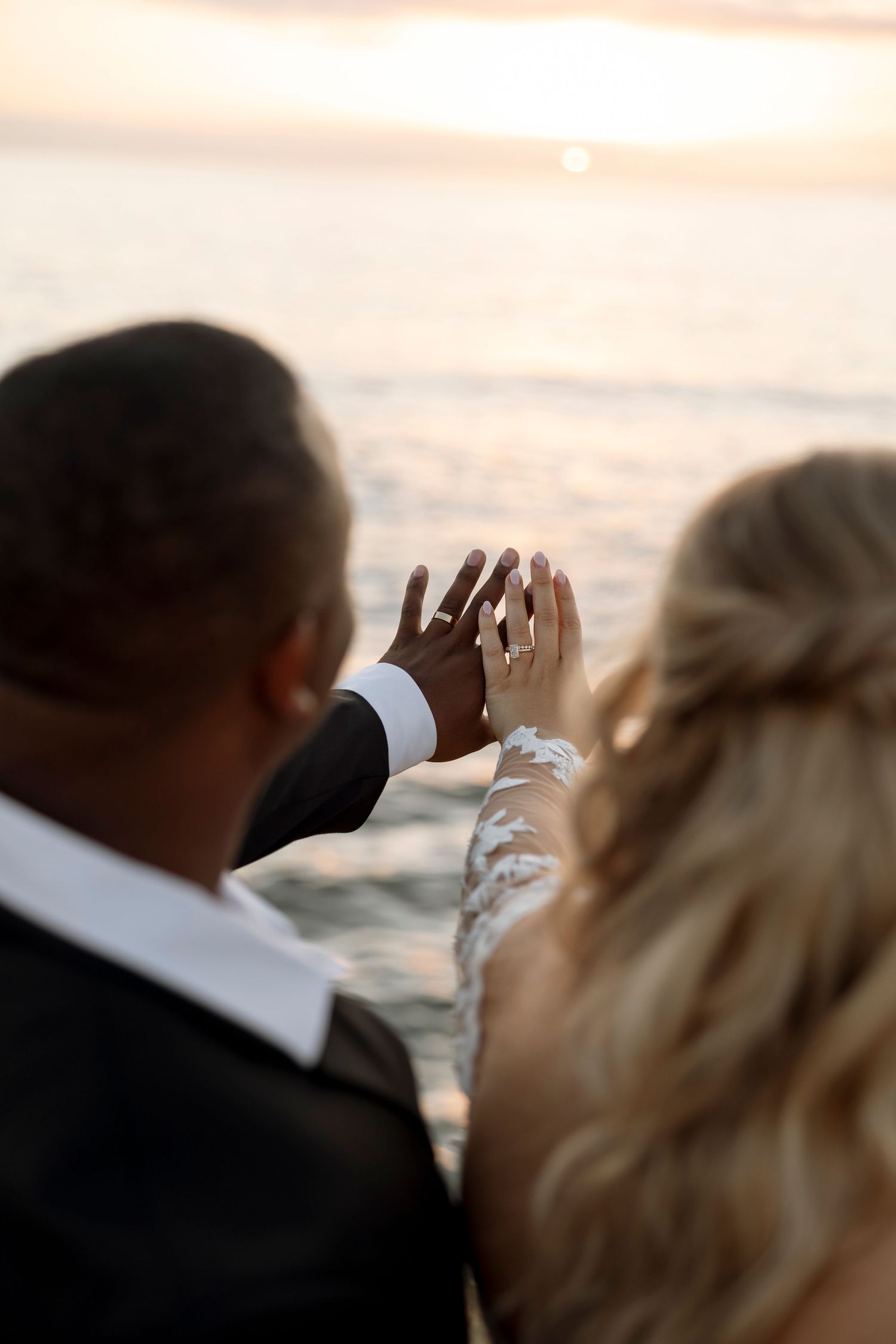 Silhouettes of a couple watching the sunset over the ocean during their wedding celebration.