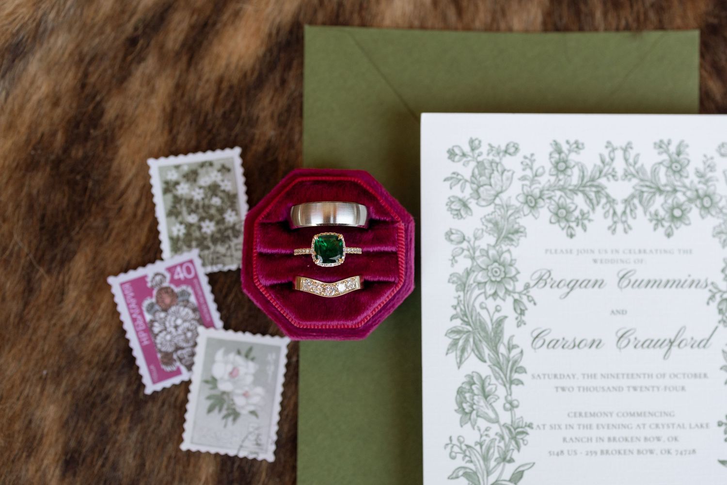 Wedding invitation with floral design alongside vintage stamps and burgundy ring box.