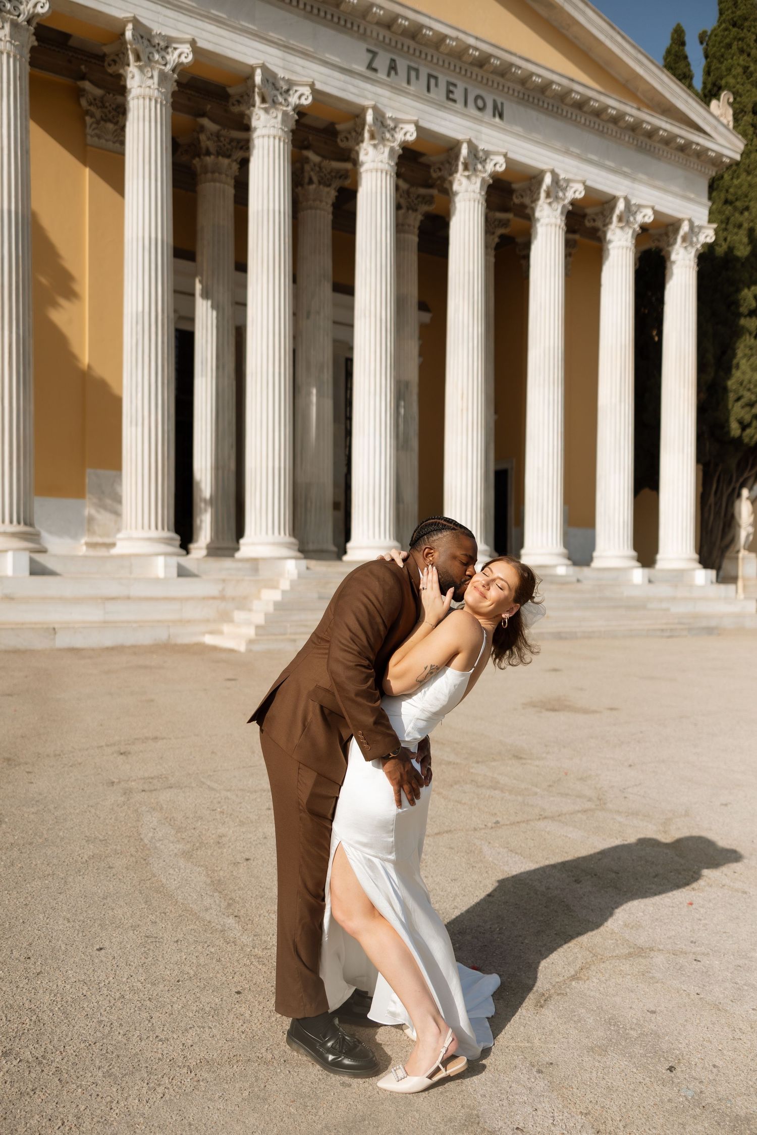 Couple shares romantic dance pose outside neoclassical Zappeion building.
