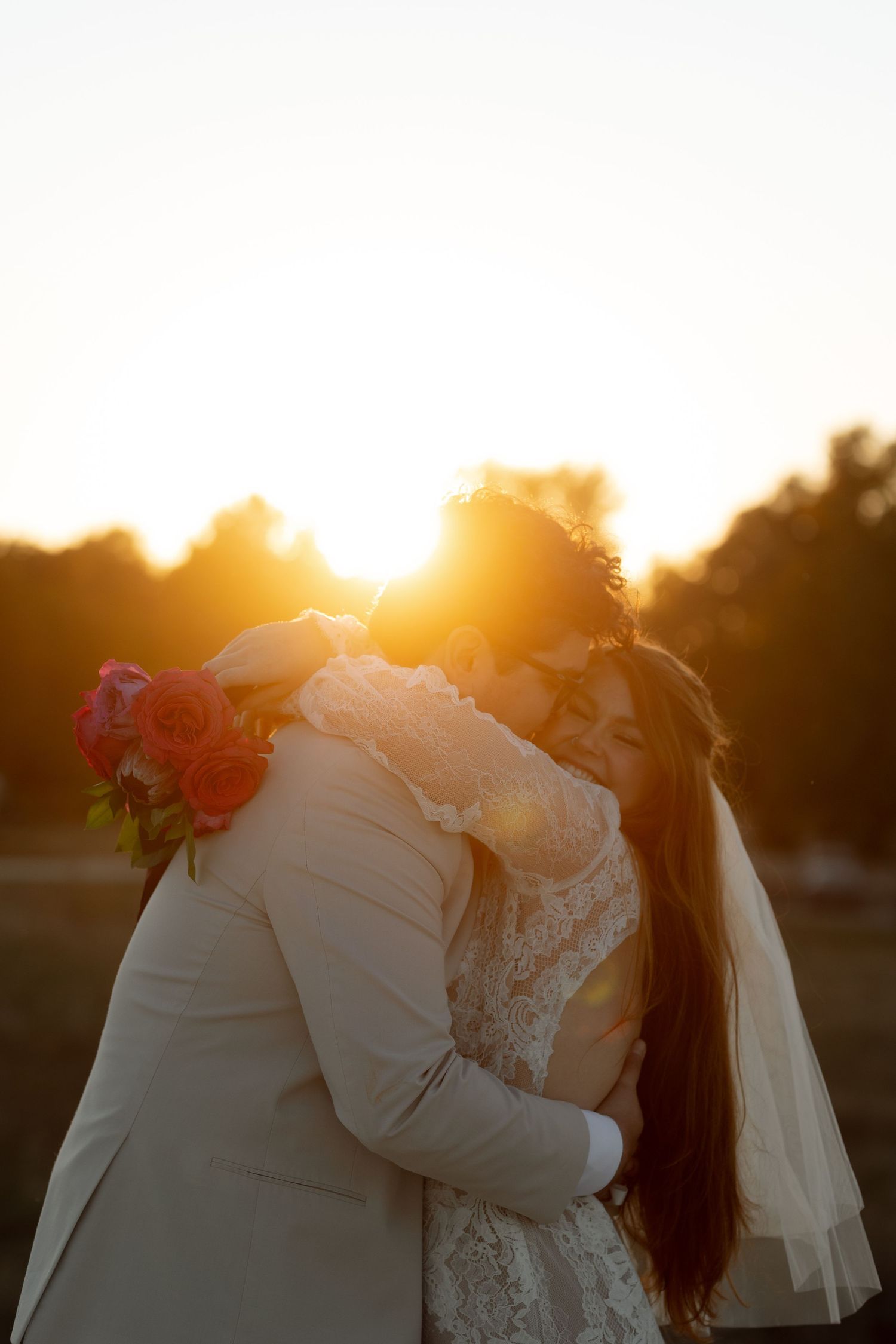 A romantic sunset wedding moment with the couple embracing in warm golden light.