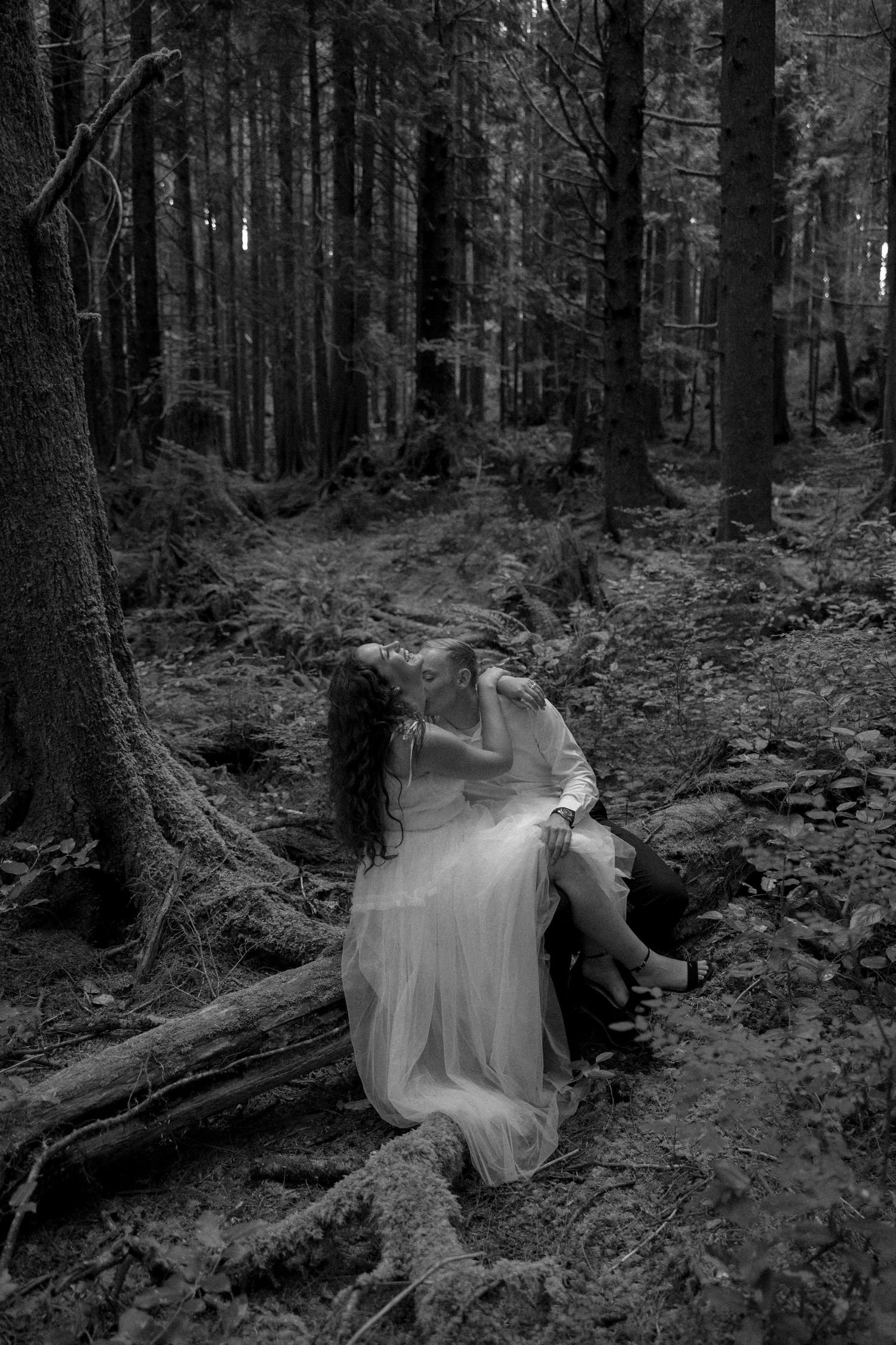 A dreamy black and white wedding photo captured in a misty forest setting.