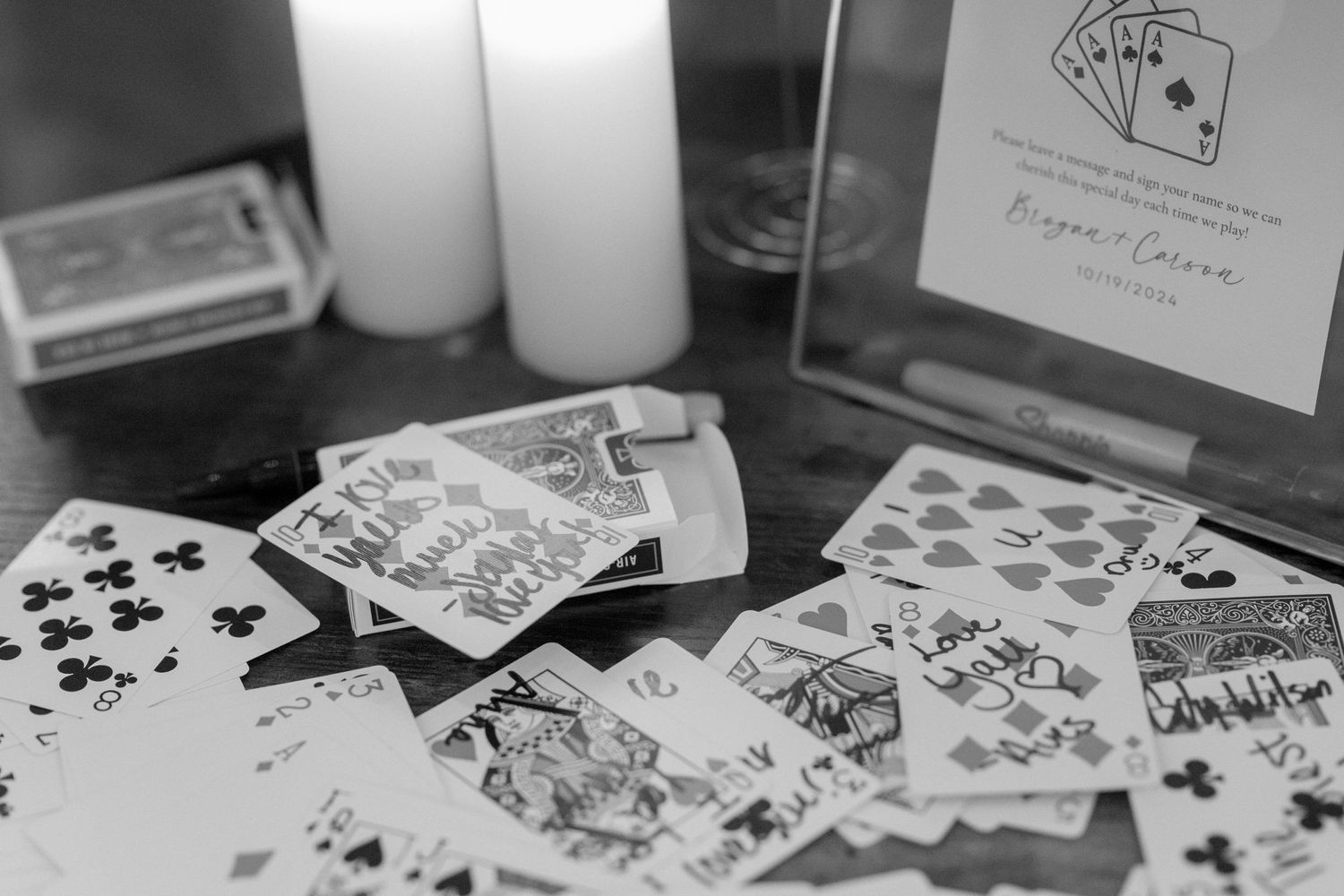 Playing cards scattered on a table with candles in black and white photography.