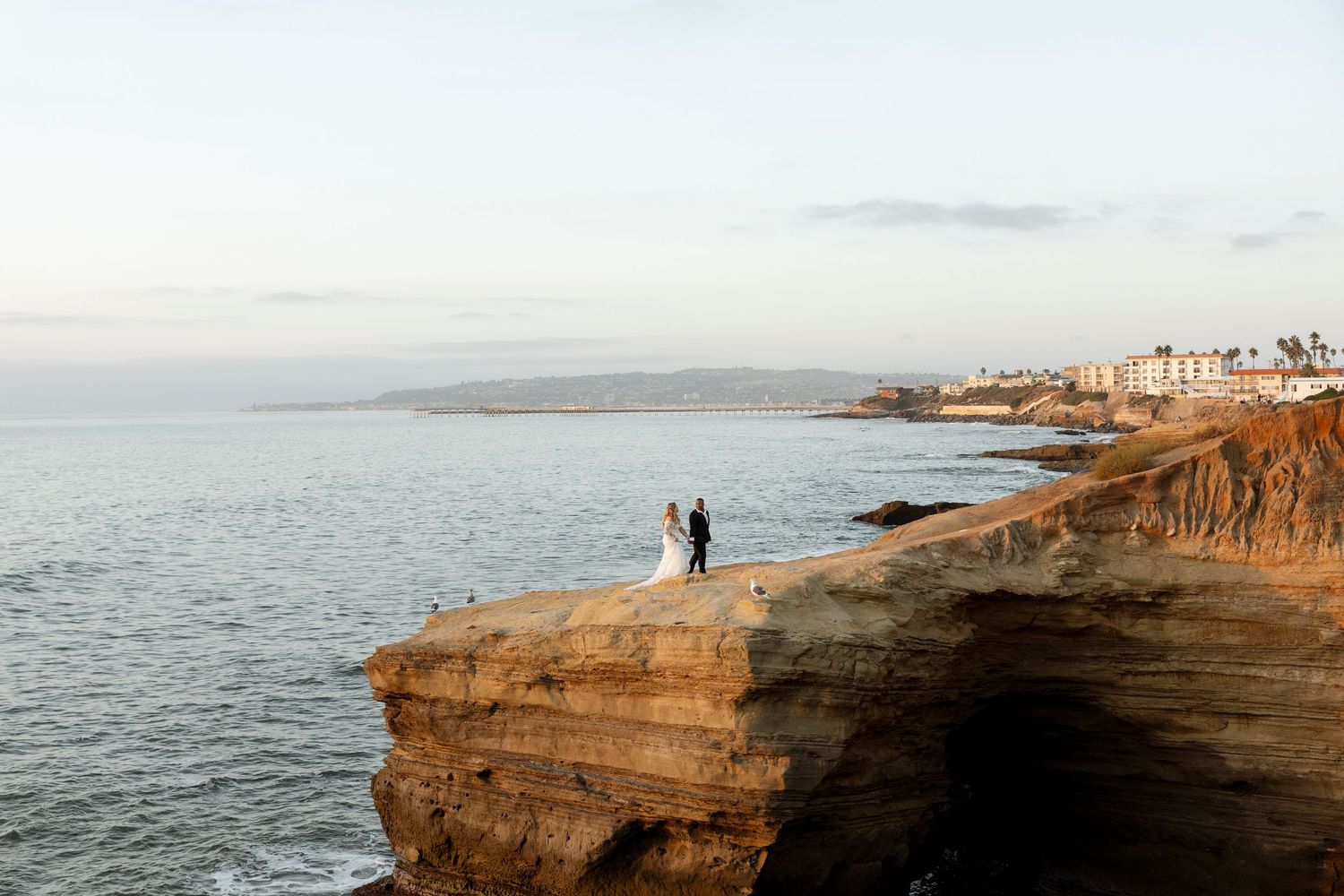 Scenic coastal cliffs at Sunset Cliffs Natural Park in San Diego with waves crashing against rocky shoreline at dusk.