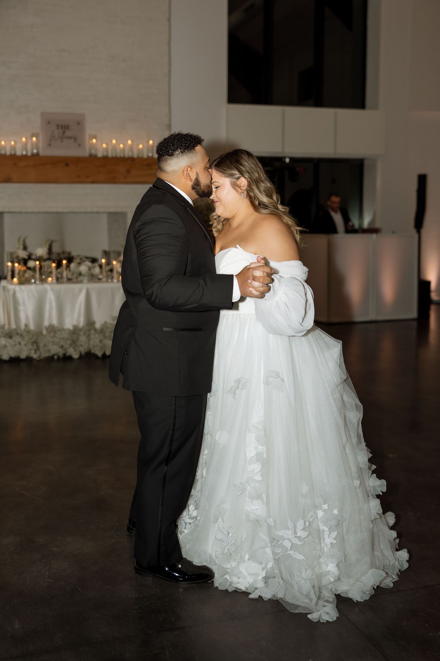 Romantic first dance between newlyweds in elegant reception venue with ambient lighting.
