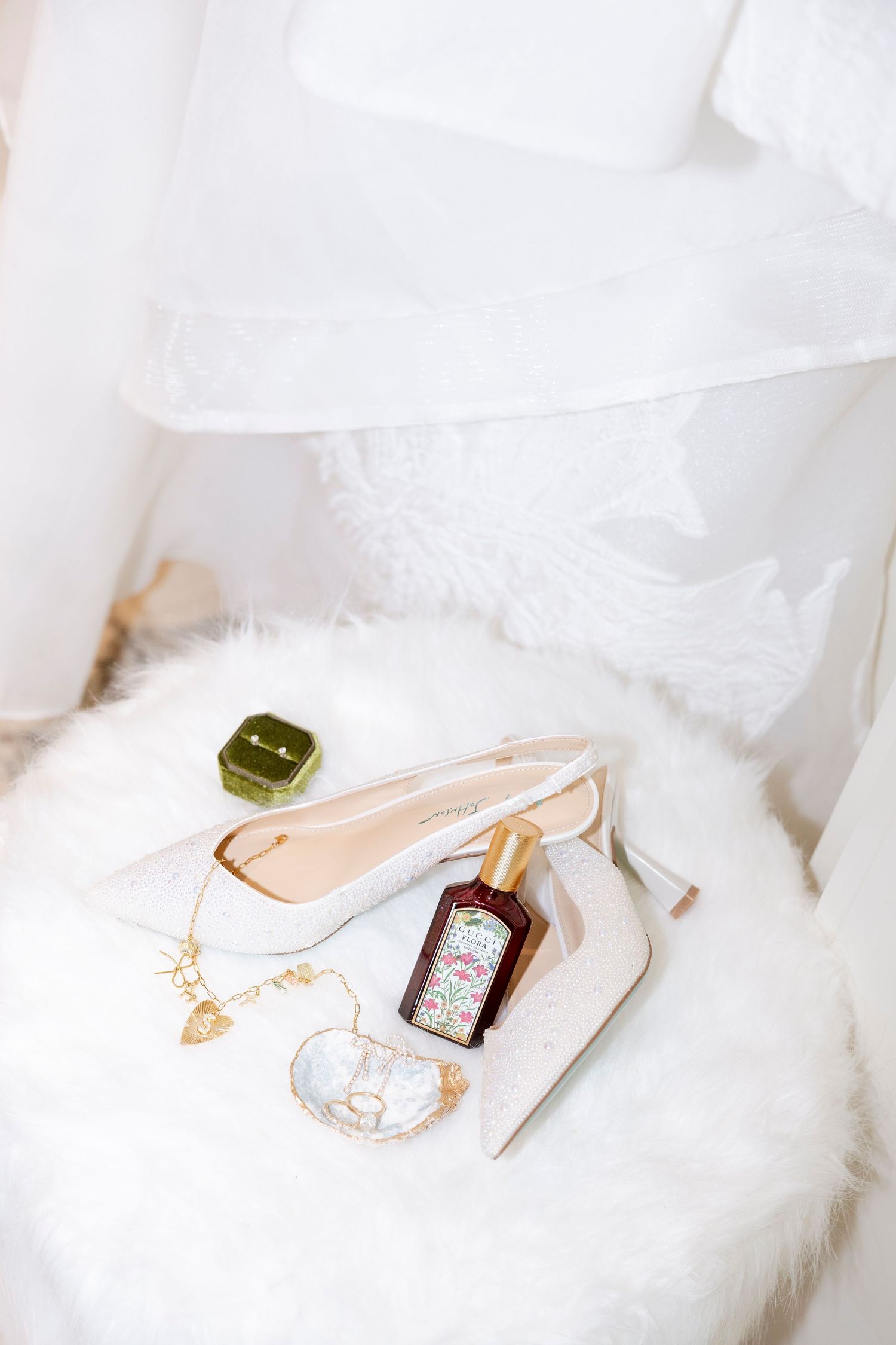 White bridal heels with crystal embellishments displayed on soft white fur.
