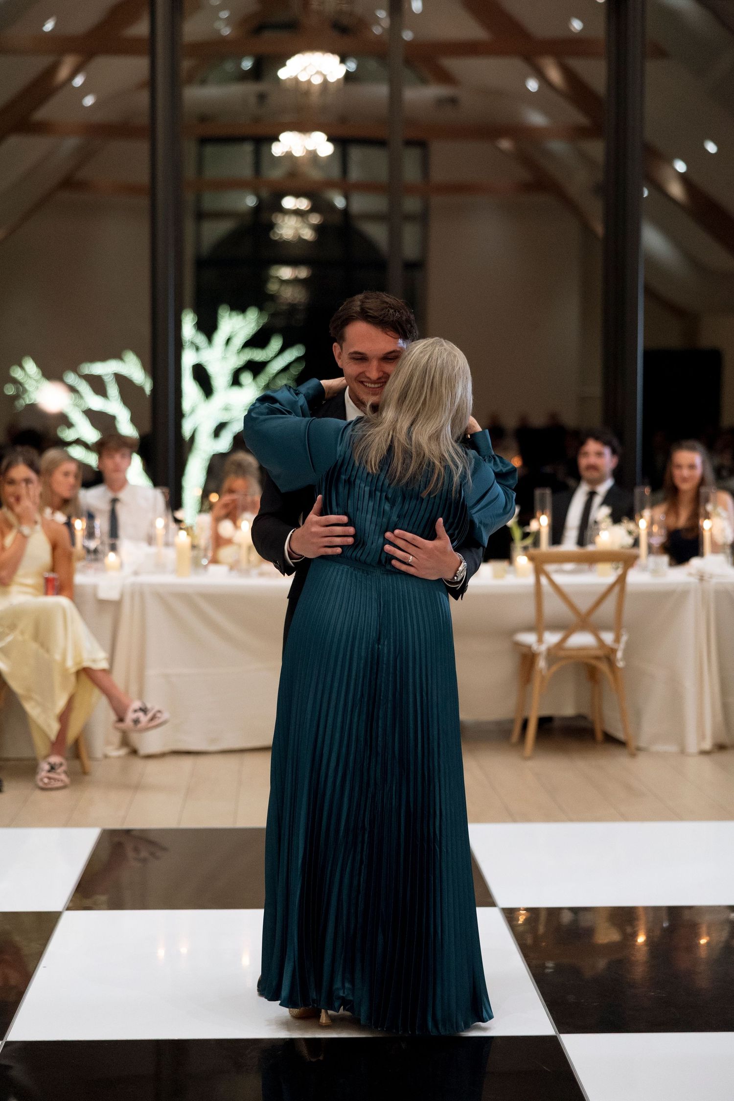 Couple sharing an intimate dance moment on black and white checkered floor at wedding reception.