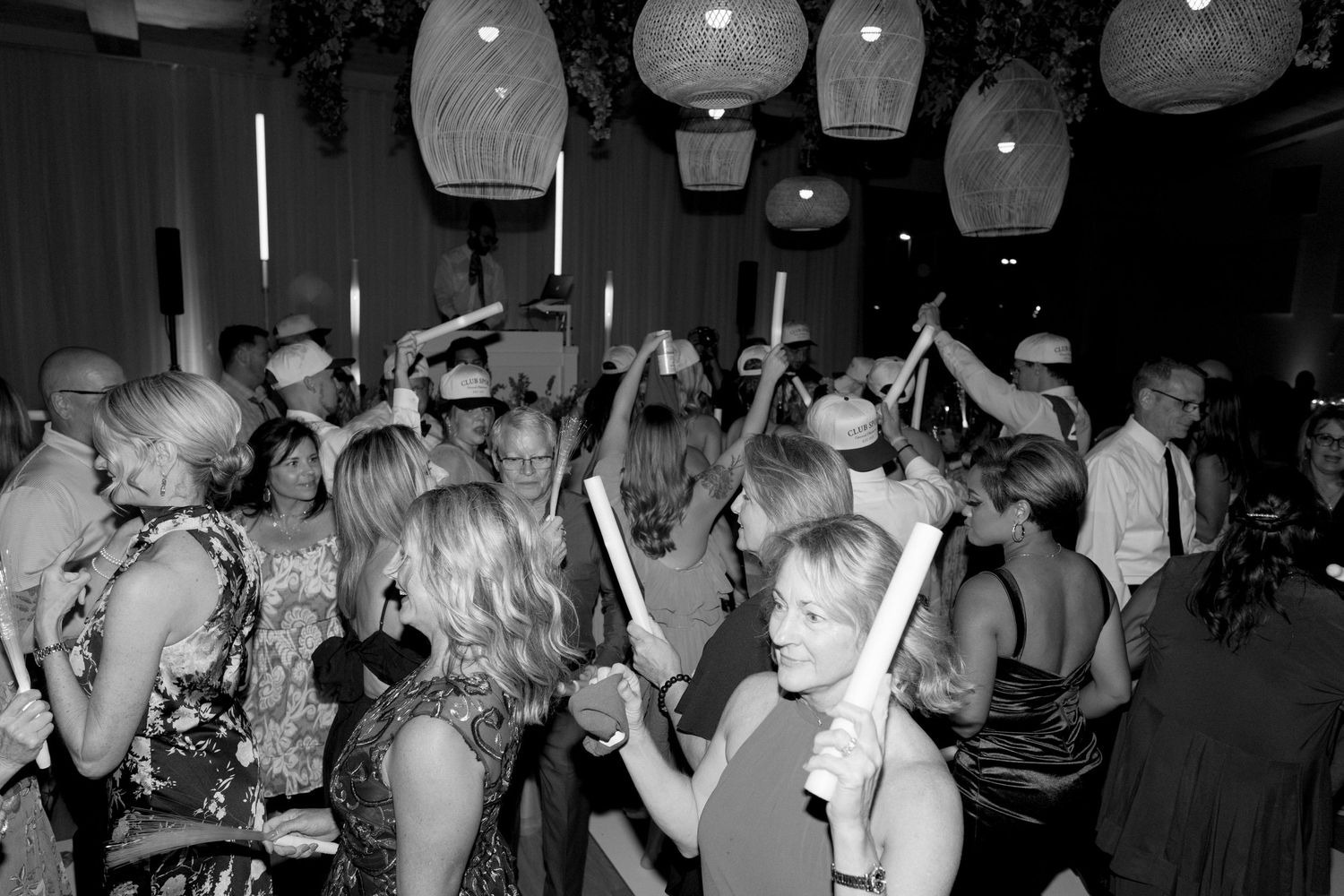 People dancing and socializing in a dimly lit nightclub with glowing lanterns hanging from the ceiling.