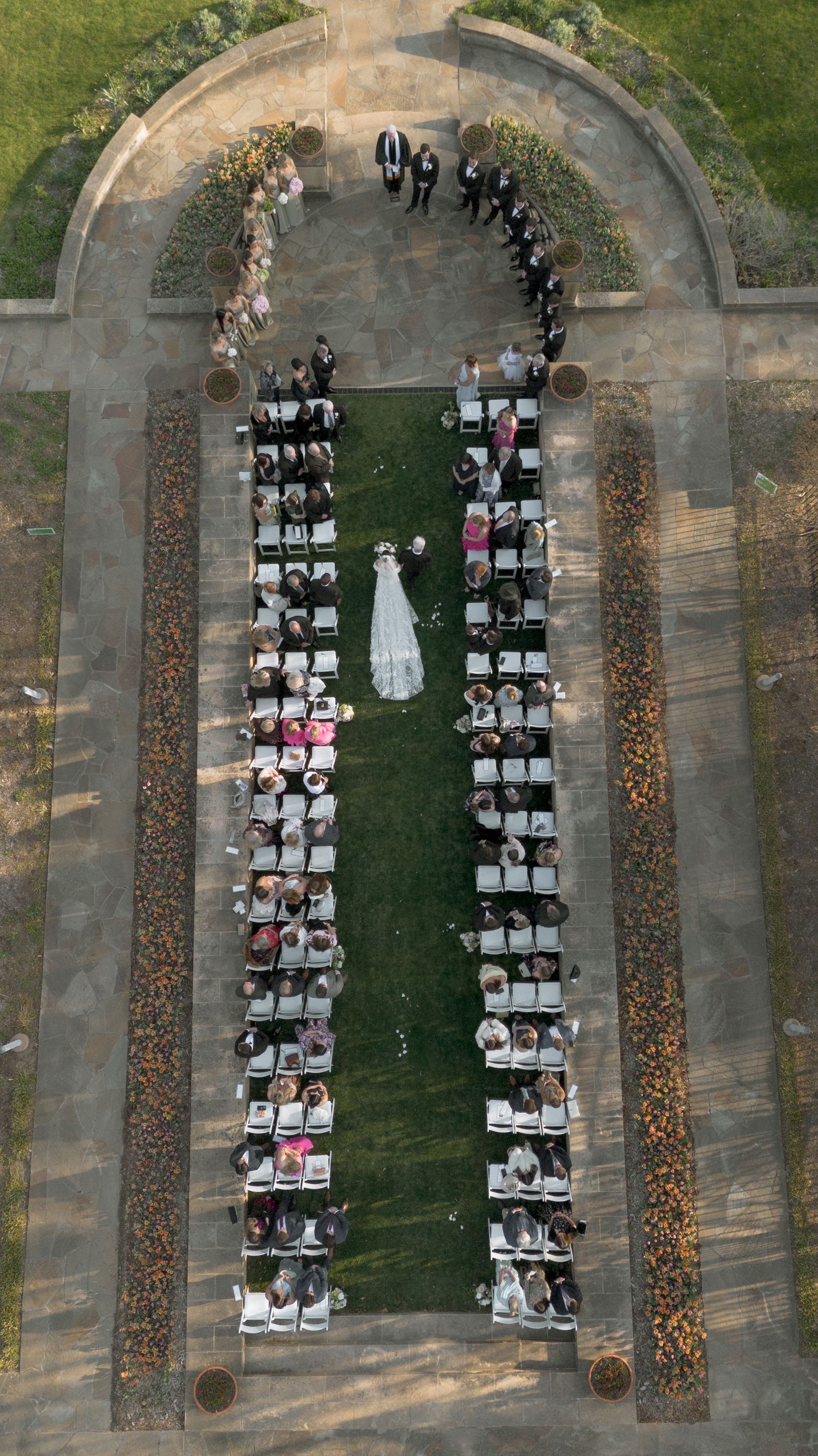 Stunning aerial drone view of outdoor wedding ceremony with guests seated in symmetrical rows.