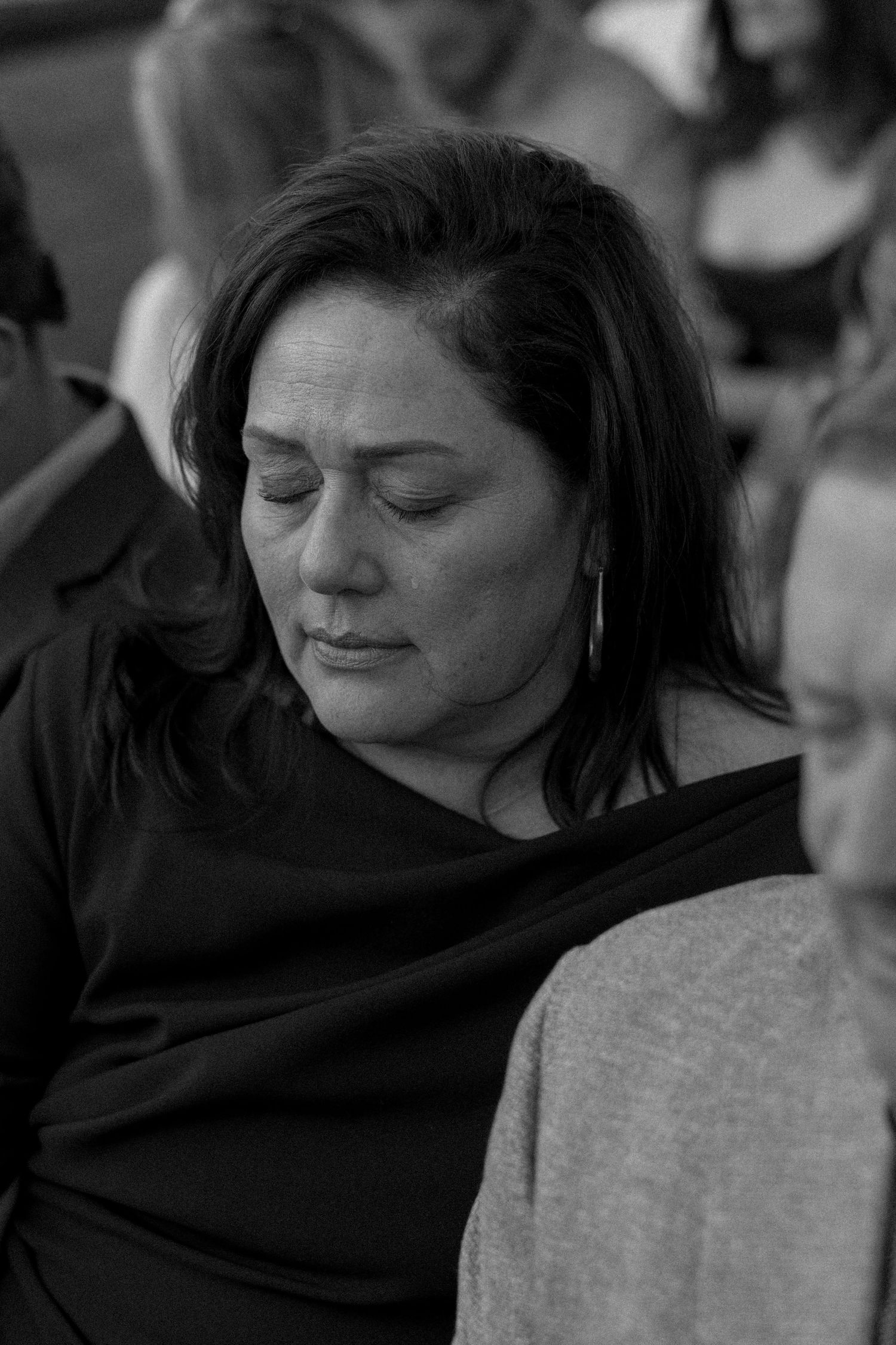 A wedding guest in black attire rests with eyes closed during the ceremony.