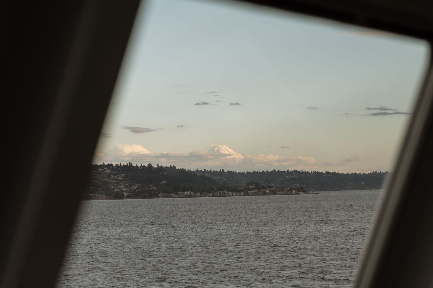 Snow-capped Mount Rainier visible through ferry window across Puget Sound.