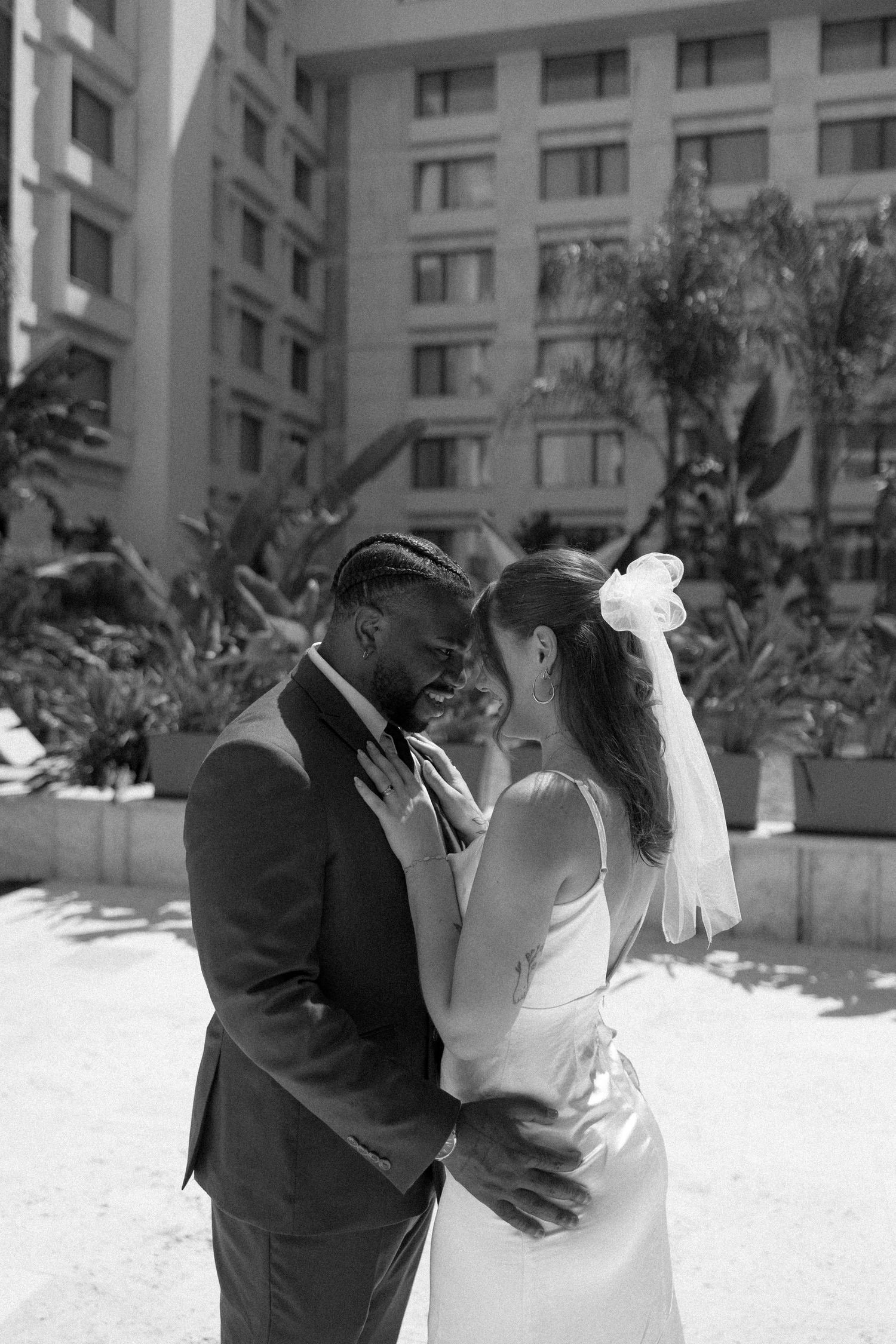 Black and white photo of a romantic wedding moment in a courtyard setting.