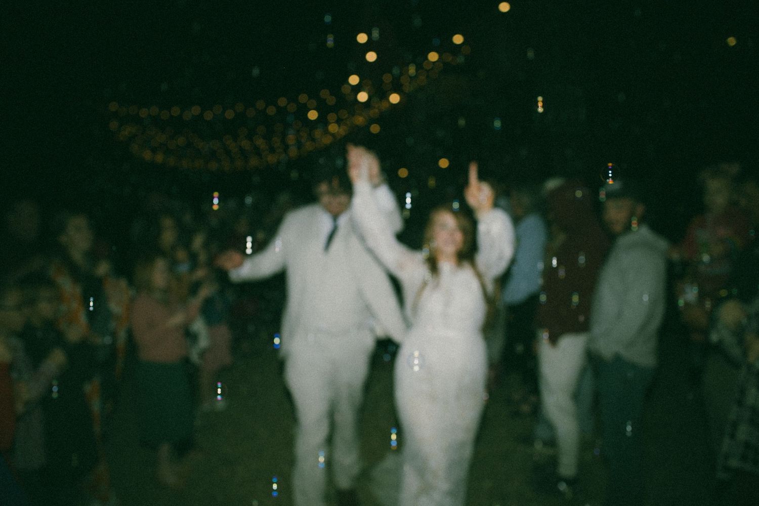 A blurred motion shot of dancing celebration under twinkle lights at wedding reception.