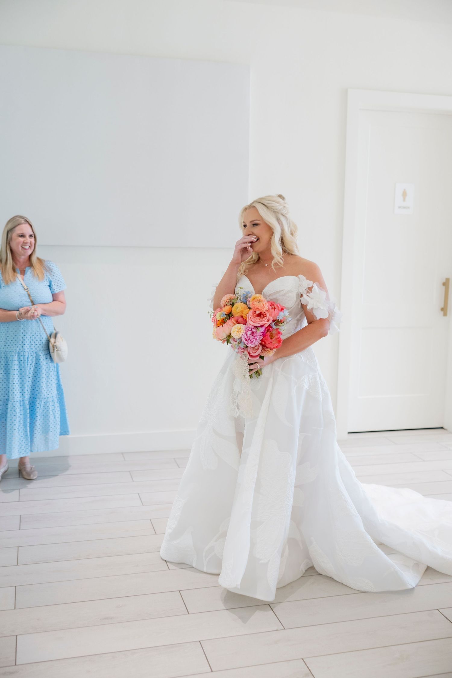 Light-filled wedding venue with white walls and elegant blue bridesmaid dresses.