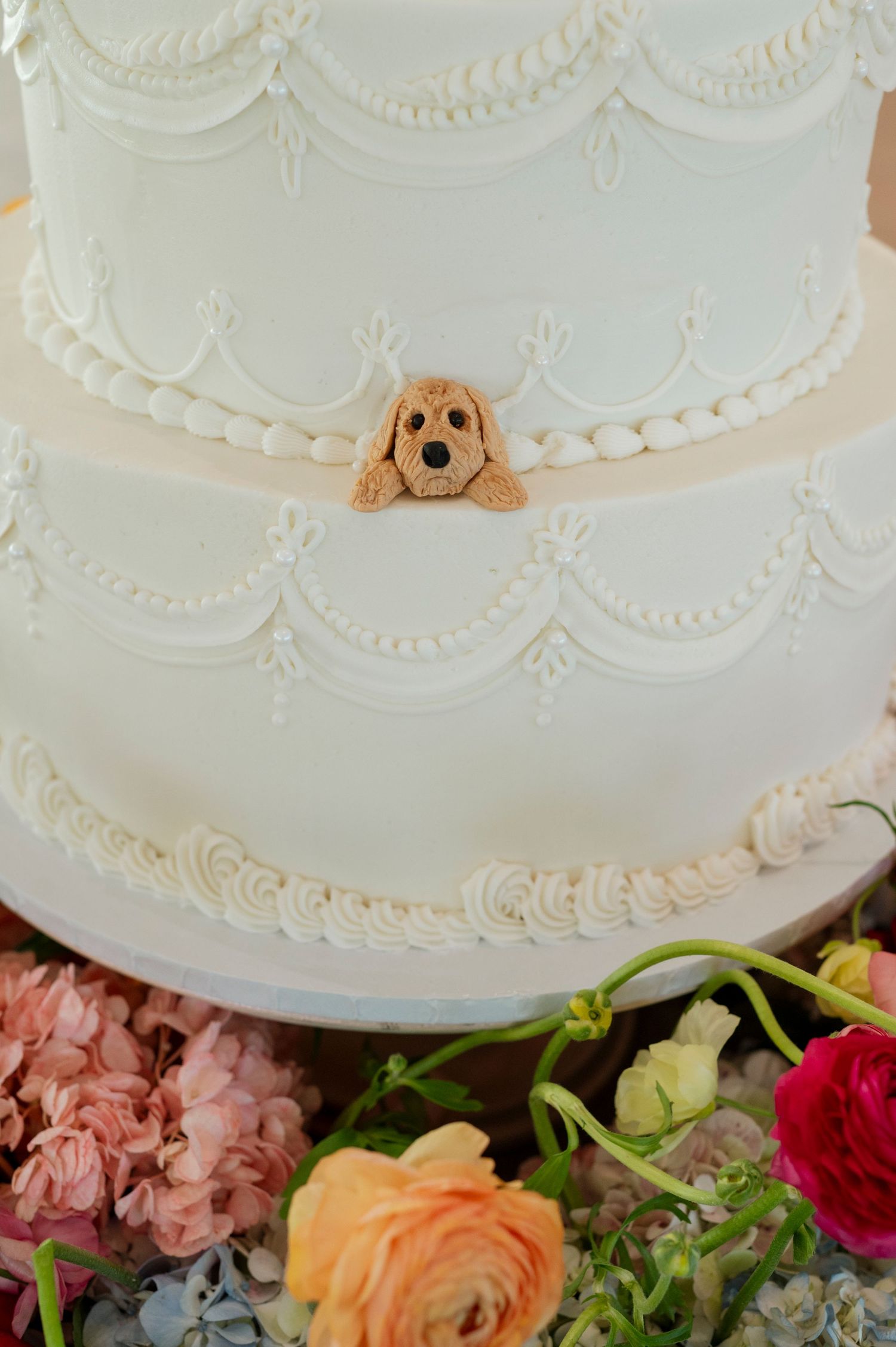 Elegant white wedding cake decorated with piped details and fresh floral accents.