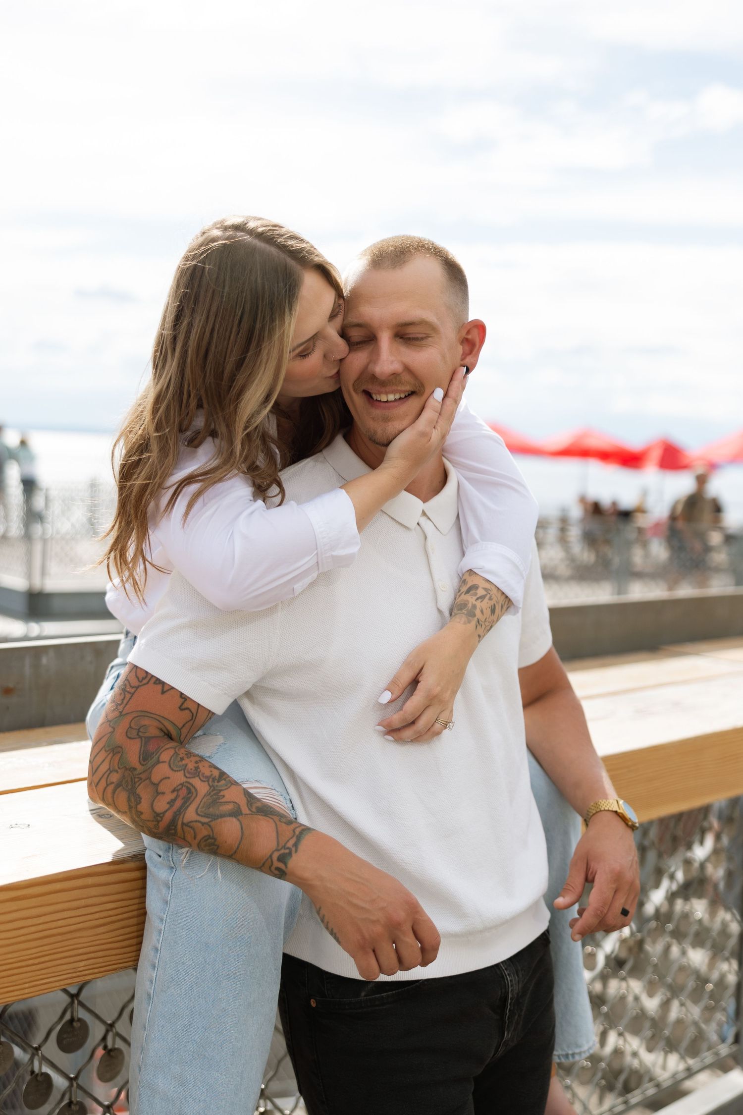 A playful couple embraces on an outdoor deck with city views.