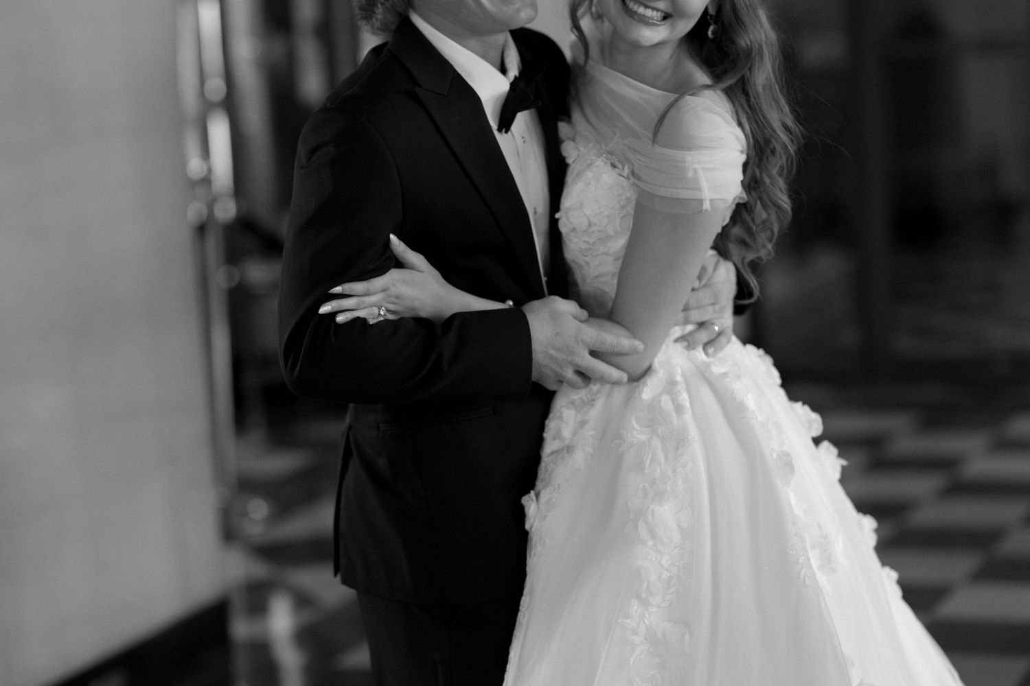 An intimate black and white wedding portrait showing an elegant ball gown and classic tuxedo.